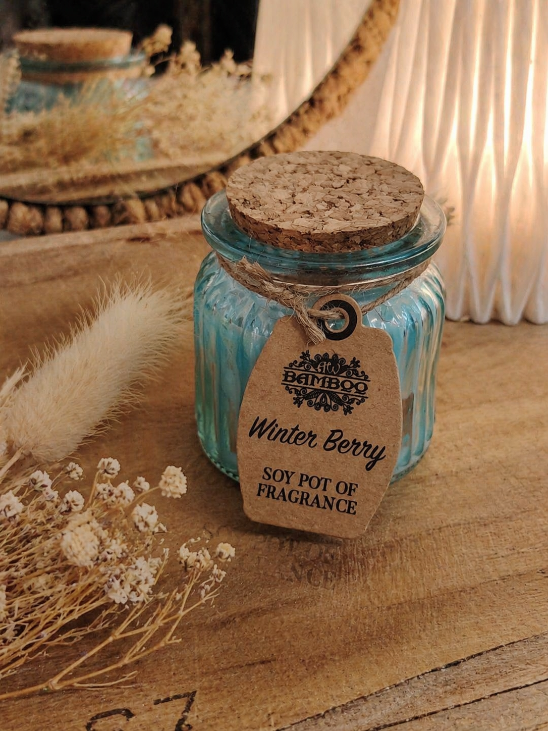 Bougie Winter Berry en cire de soja sur plateau en bois avec fleurs séchées et vase blanc, ambiance douce et chaleureuse