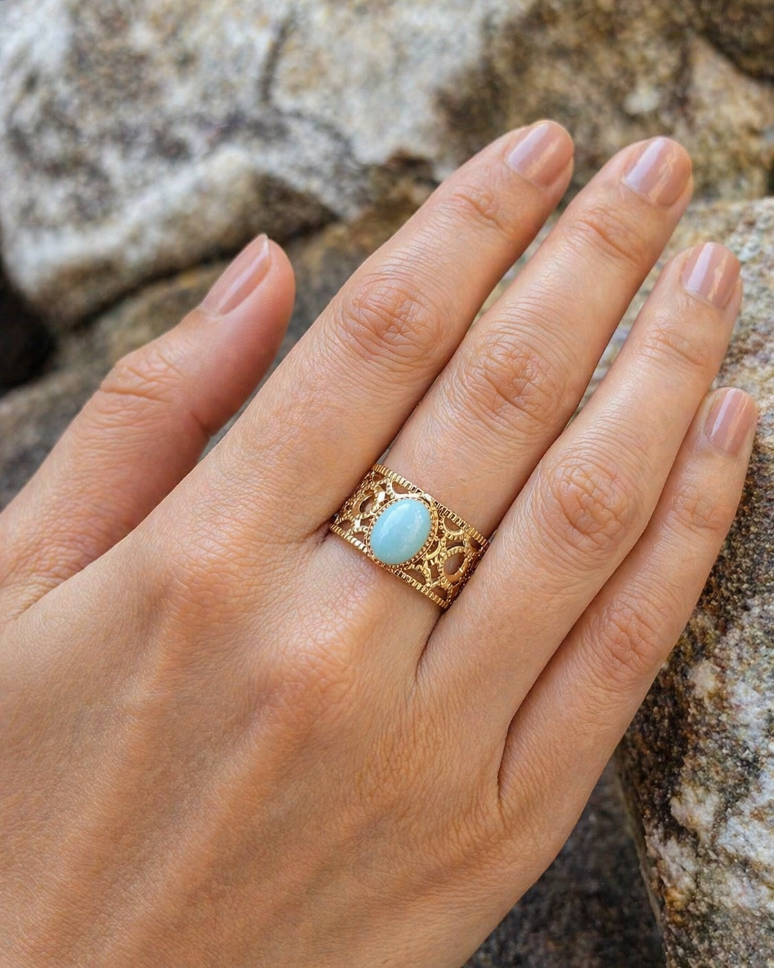 Bague dorée Amazonite portée sur la main, cabochon bleu-vert et acier inoxydable ajouré pour une allure naturelle et élégante.
