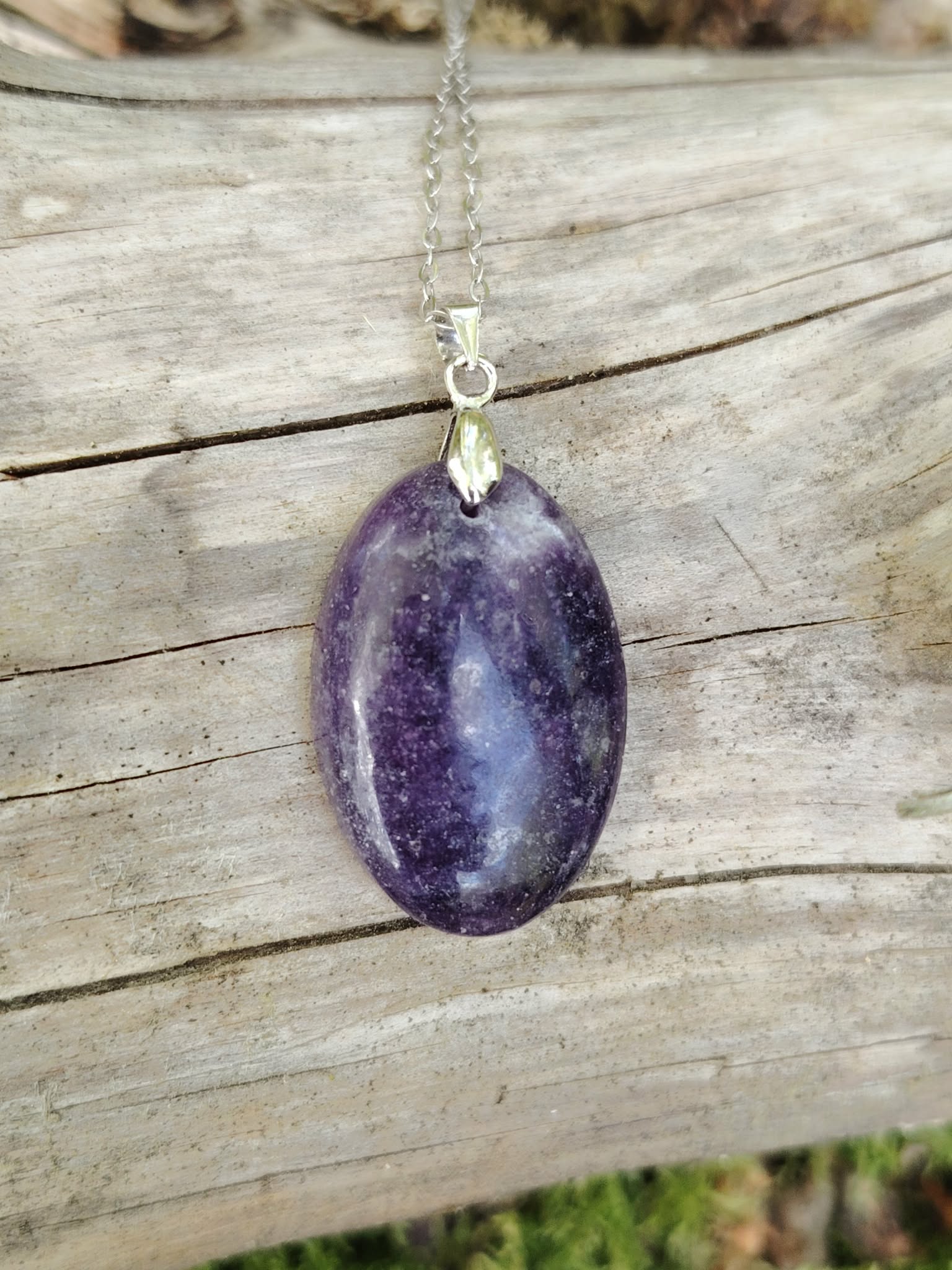 Pendentif en Lépidolite naturelle violette suspendu sur bois clair, bijou en pierre naturelle évoquant sérénité, équilibre émotionnel et douceur