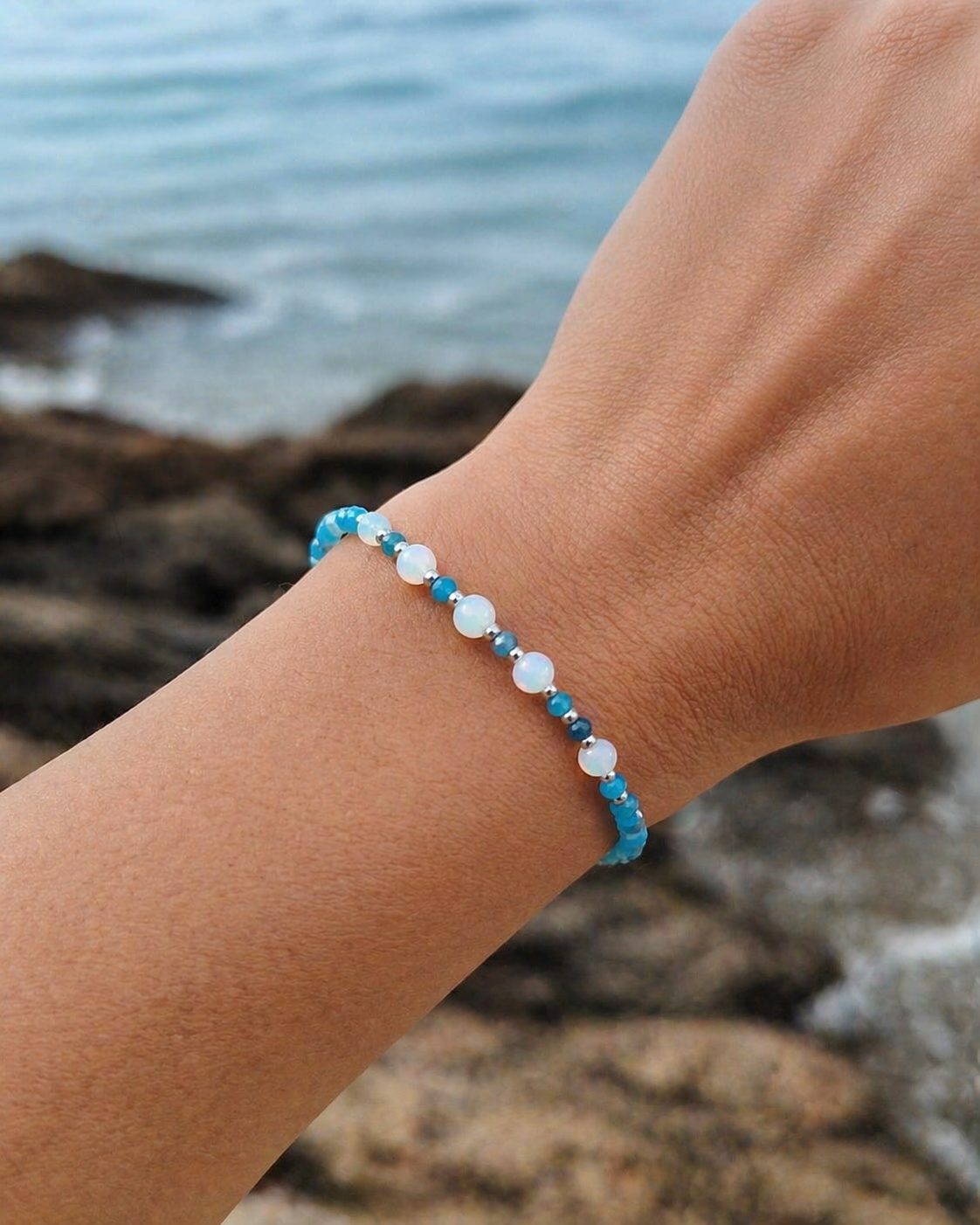 Bracelet apatite facettée et opale porté au poignet en bord de mer, création Magic Gaïa lumineuse, apaisement émotionnel.