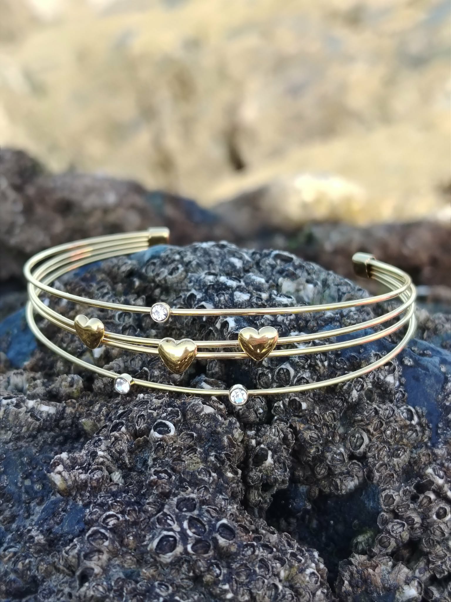 Bracelet jonc ouvert doré avec petits cœurs et strass, quadruple fils fins au style féminin, raffiné et lumineux.