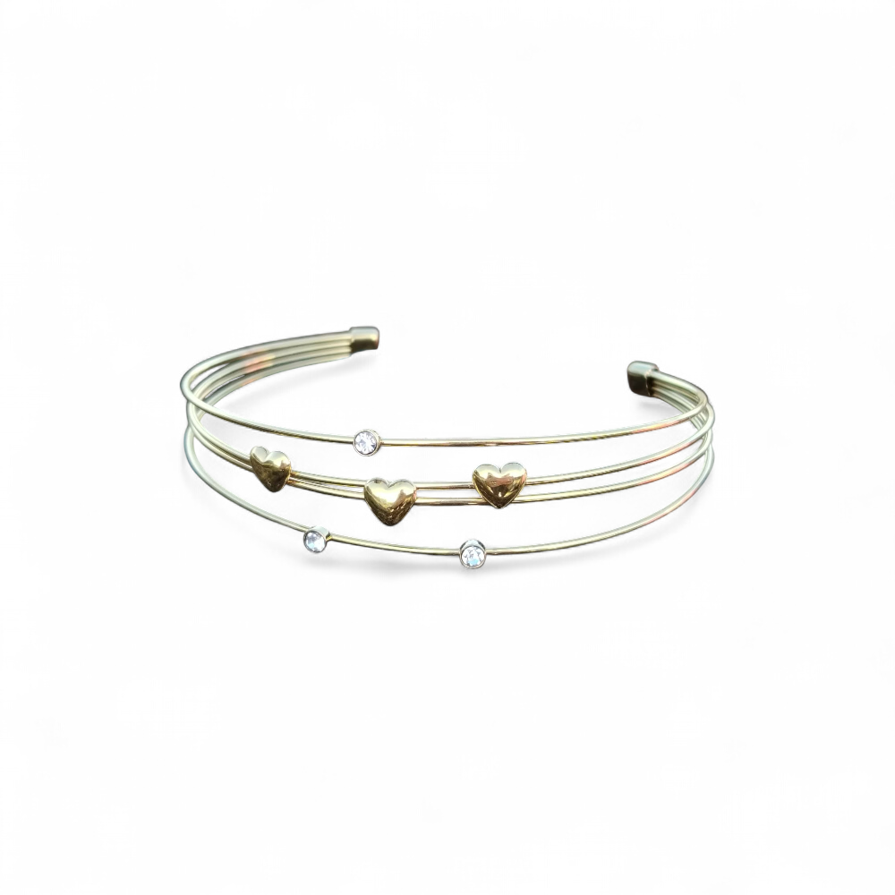 Bracelet jonc doré quadruple fils sur fond blanc, détails cœurs et strass lumineux, bijou ouvert élégant pour le poignet.