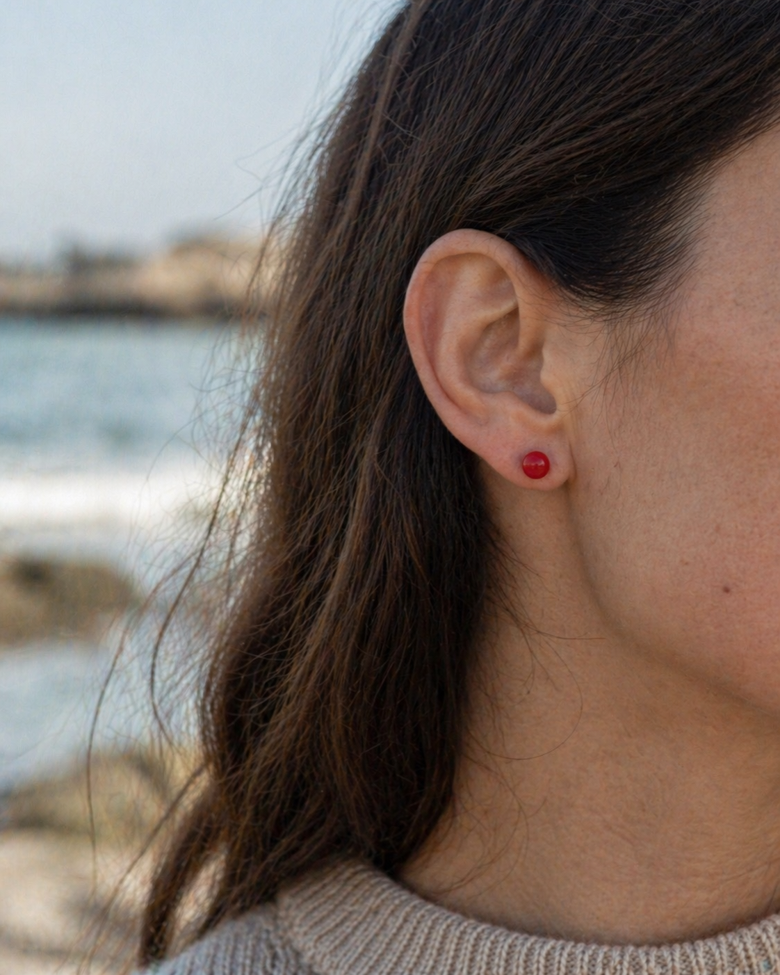 Boucles d’oreilles Cornaline portées naturellement en Bretagne, bijou rouge discret en inox 304, confiance en soi et vitalité.