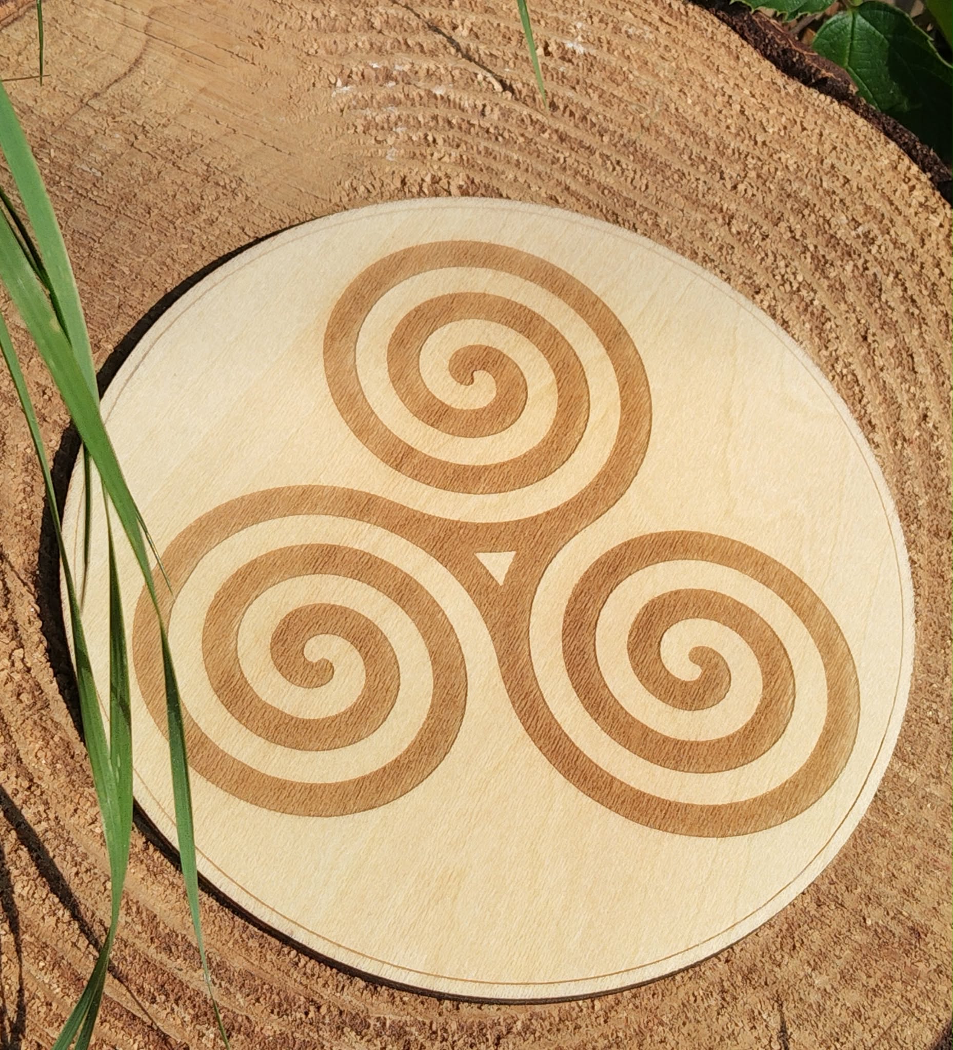 Plaque en bois Triskell sur souche naturelle en Bretagne, gravure celtique lumineuse et ambiance végétale.