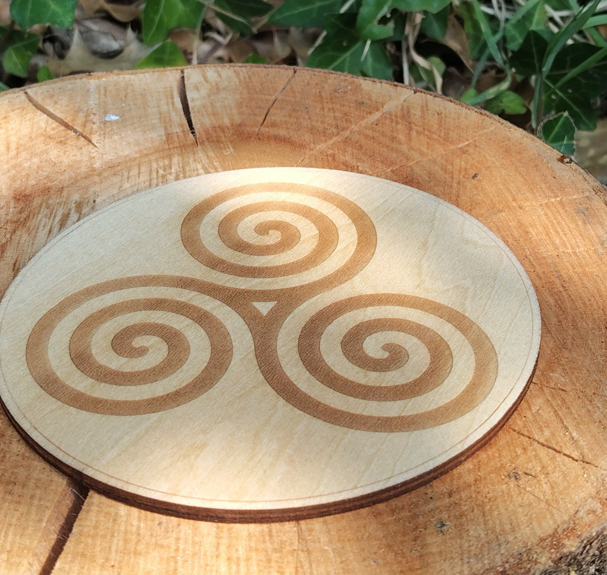Gros plan sur plaque Triskell en bois avec lierre en Bretagne, décor naturel et symbole celte d’équilibre.