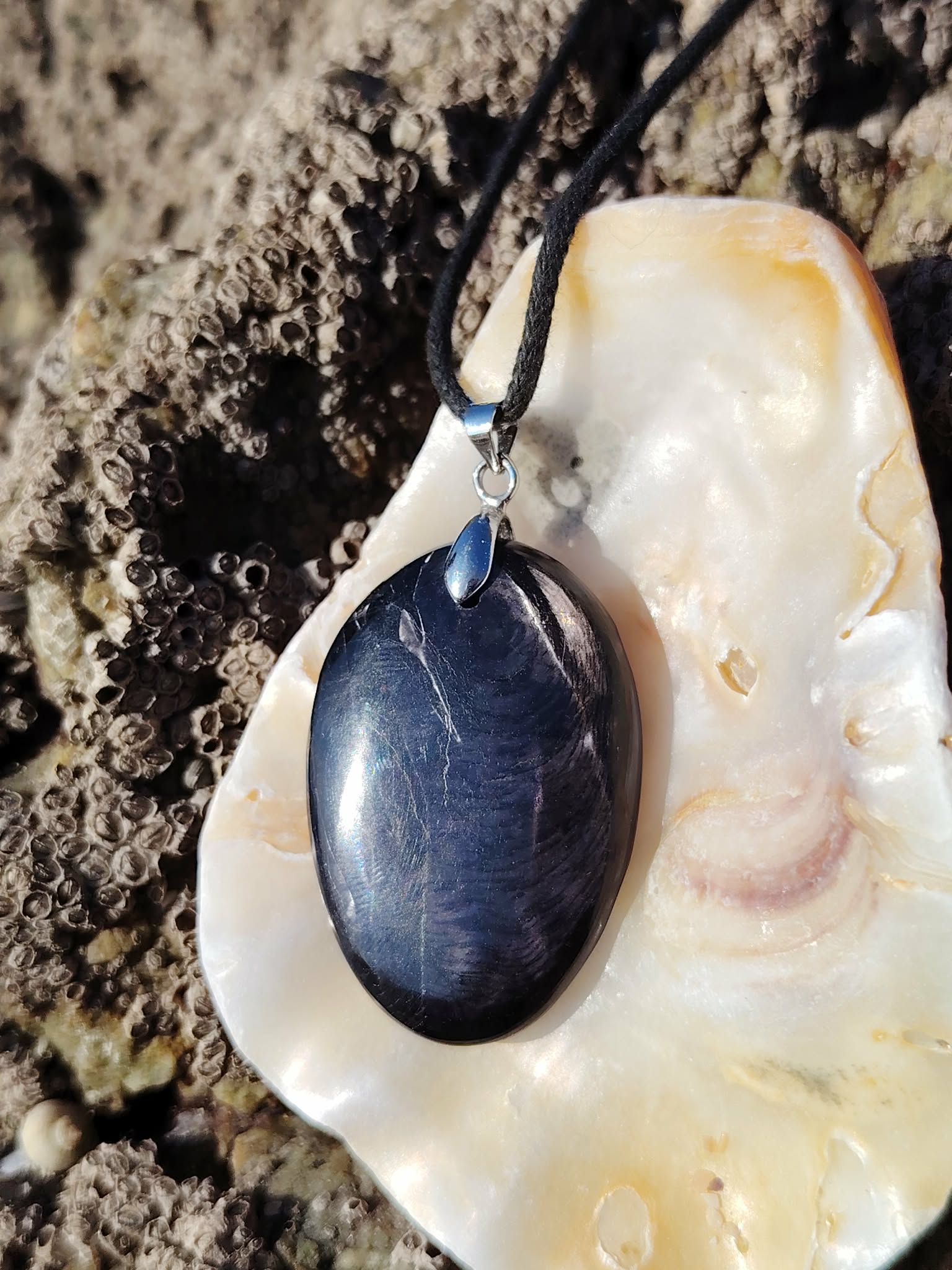 Pendentif Hyperstène sur coquillage en Bretagne avec cordon noir, pierre sombre à reflets doux, introspection et équilibre émotionnel