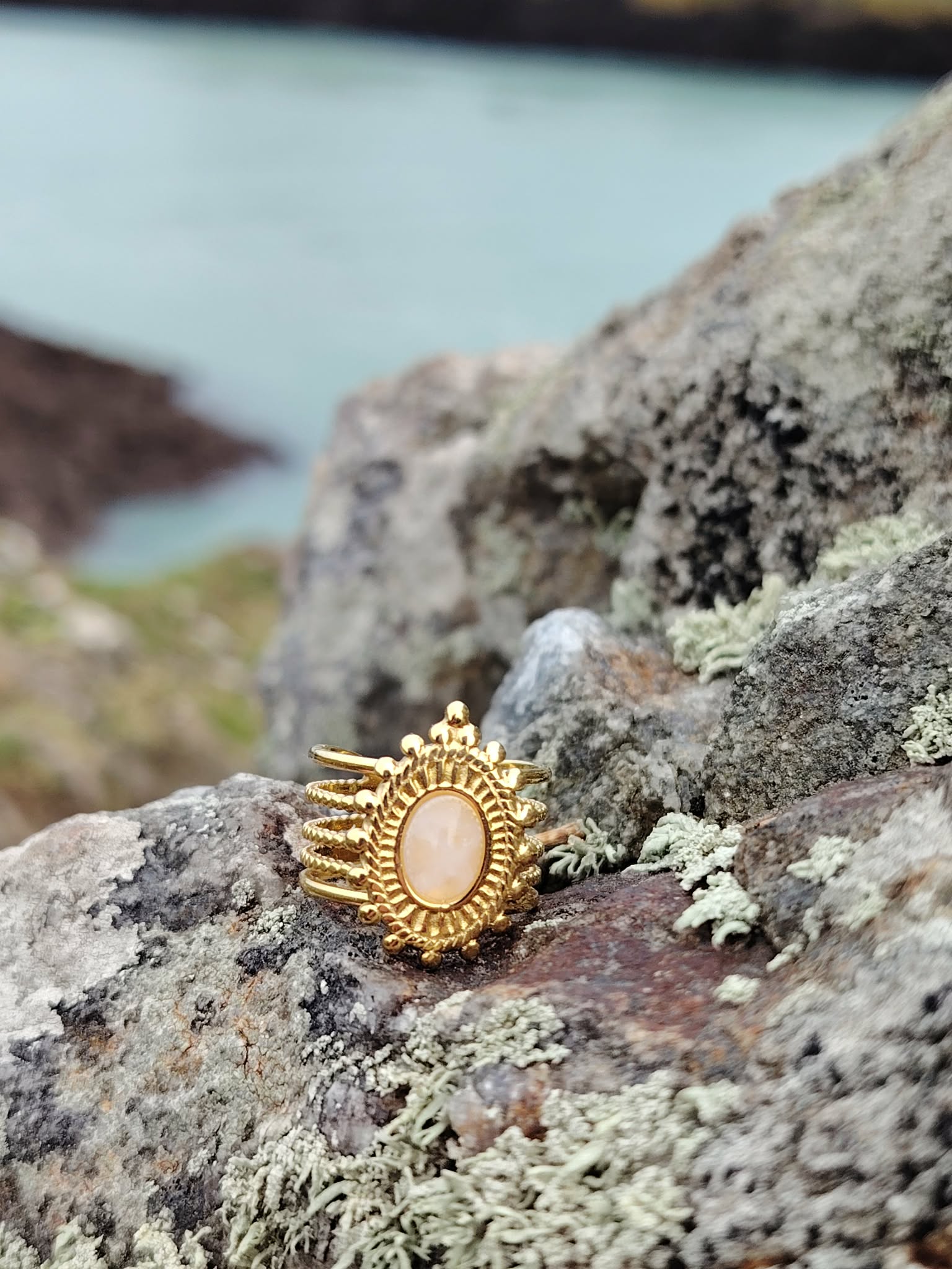 Bague dorée ajustable multi-rangs avec pierre de soleil rosée sur support clair en Bretagne, bijou lumineux évoquant joie et douceur