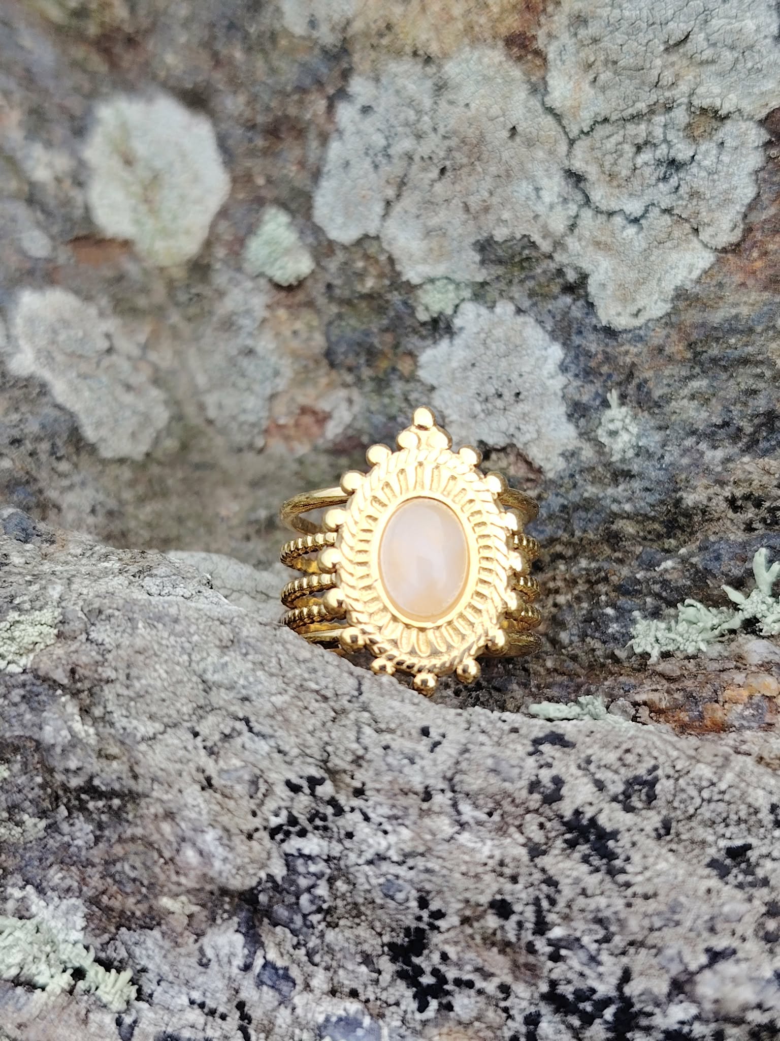 Bague dorée ajustable avec pierre de soleil rosée sur décor minéral en Bretagne, bijou féminin aux reflets doux et rayonnement intérieur