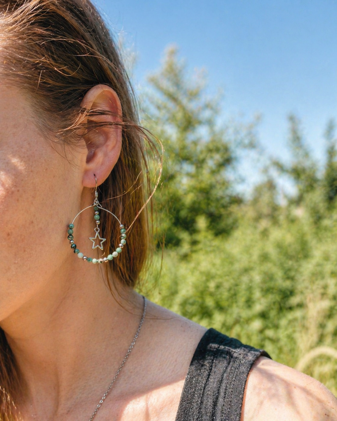 Boucles d’oreilles turquoise africaine portées en lumière naturelle, perles vert bleuté et petites étoiles argentées.