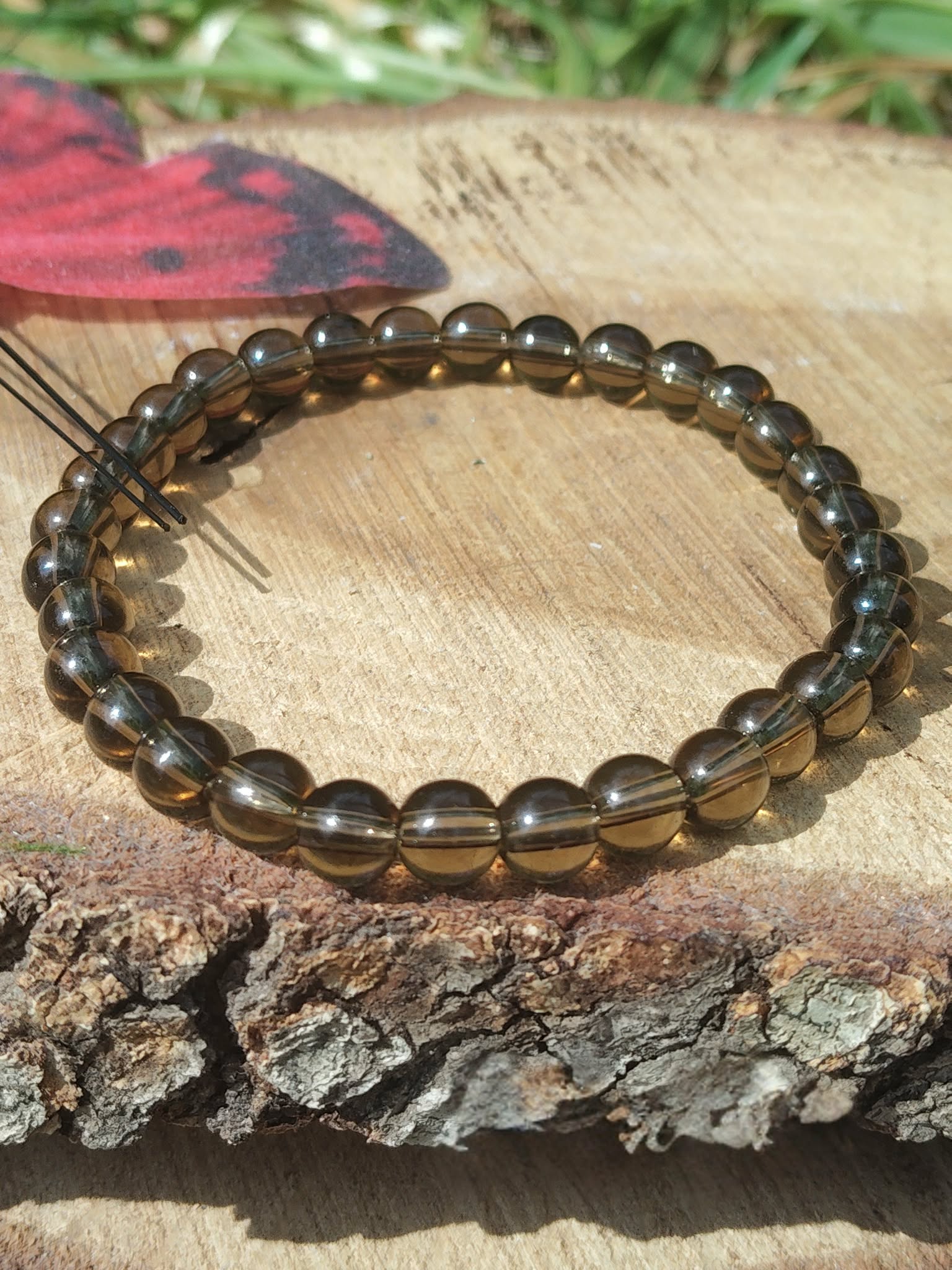 Bracelet Quartz fumé 6 mm sur fond naturel, perles brunes translucides aux reflets fumés, ancrage et clarté intérieure.