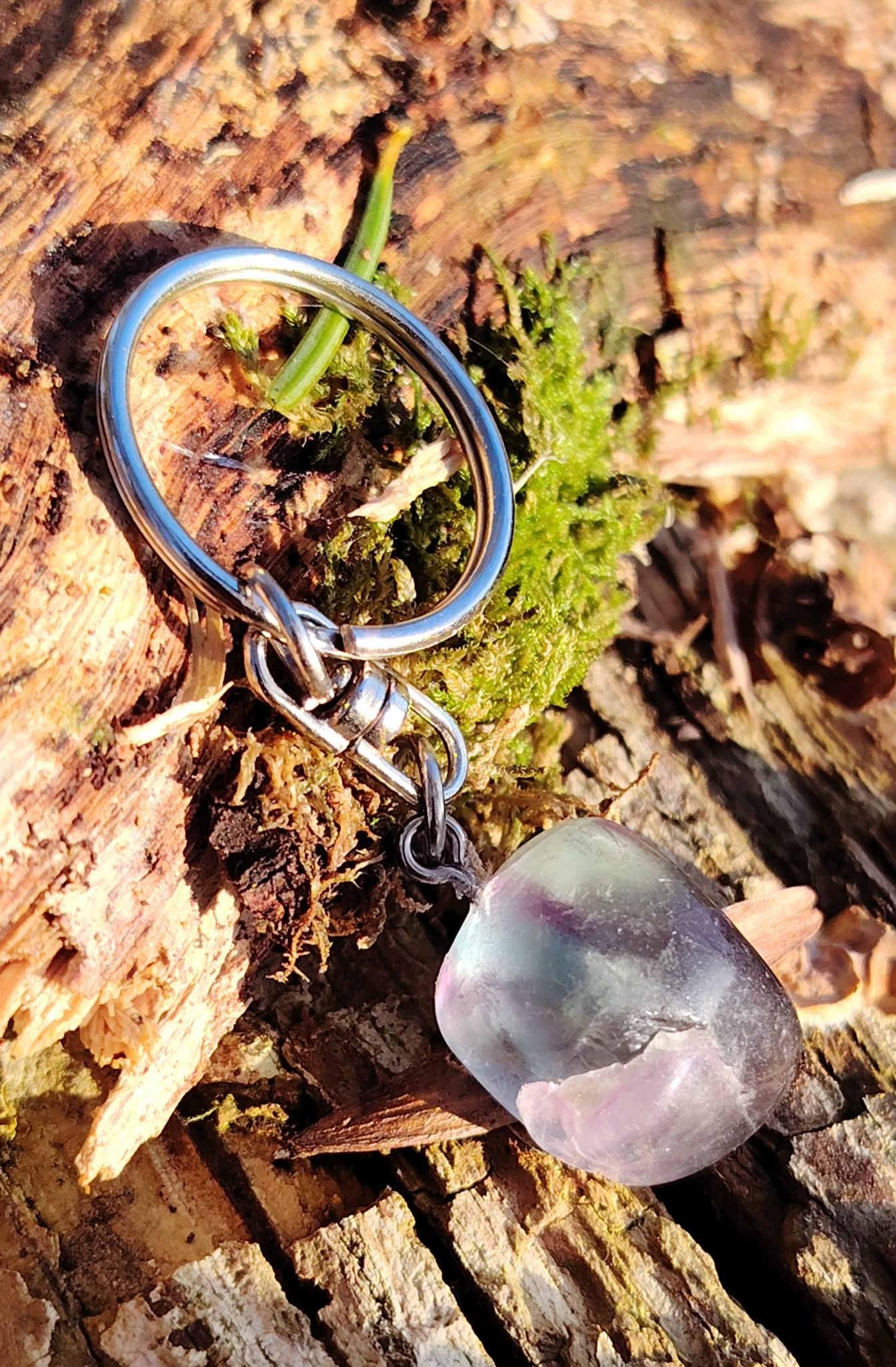 Bijou de sac Fluorite naturelle sur décor minéral en Bretagne, pierre multicolore polie et mousqueton argenté.