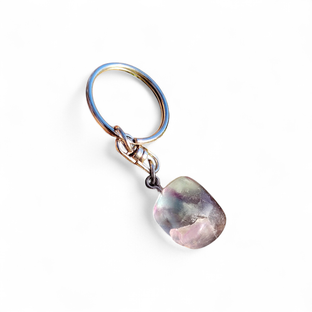Porte-clés bijou de sac Fluorite multicolore posé sur fond blanc, pierre polie verte violette et attache argentée.
