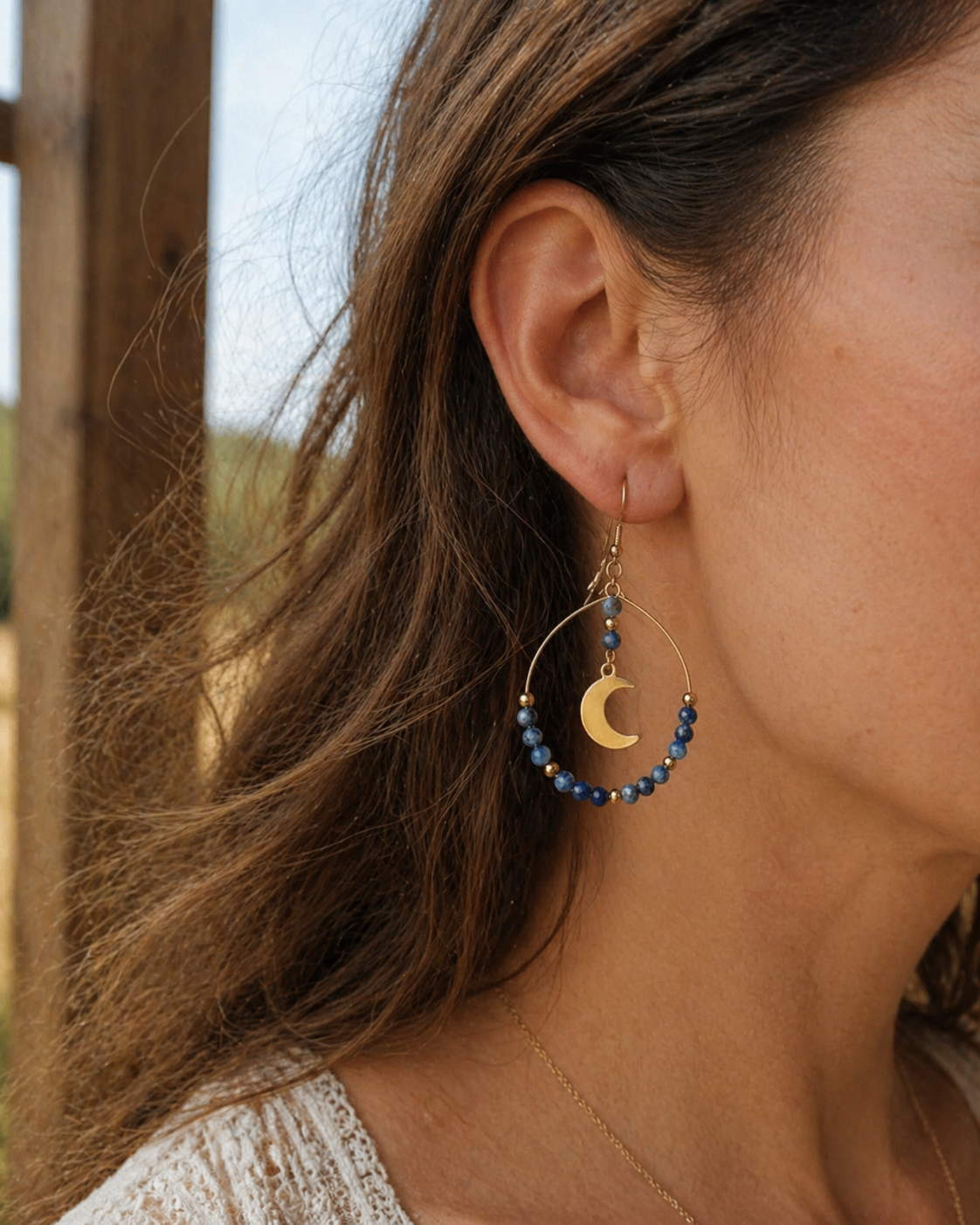 Boucle d’oreille lune portée en situation naturelle, lapis lazuli bleu et acier doré pour une touche élégante et intuitive.