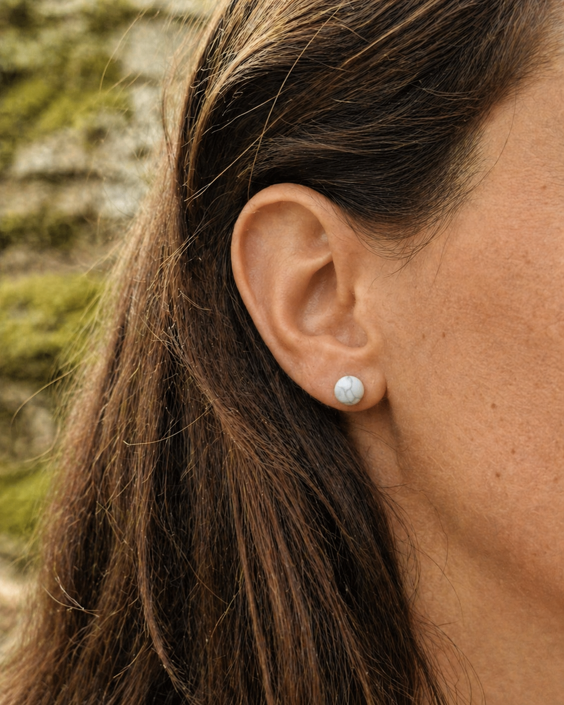 Boucle d’oreille puce Howlite 6 mm portée en situation naturelle, pierre blanche veinée sur acier argenté pour douceur et recentrage.