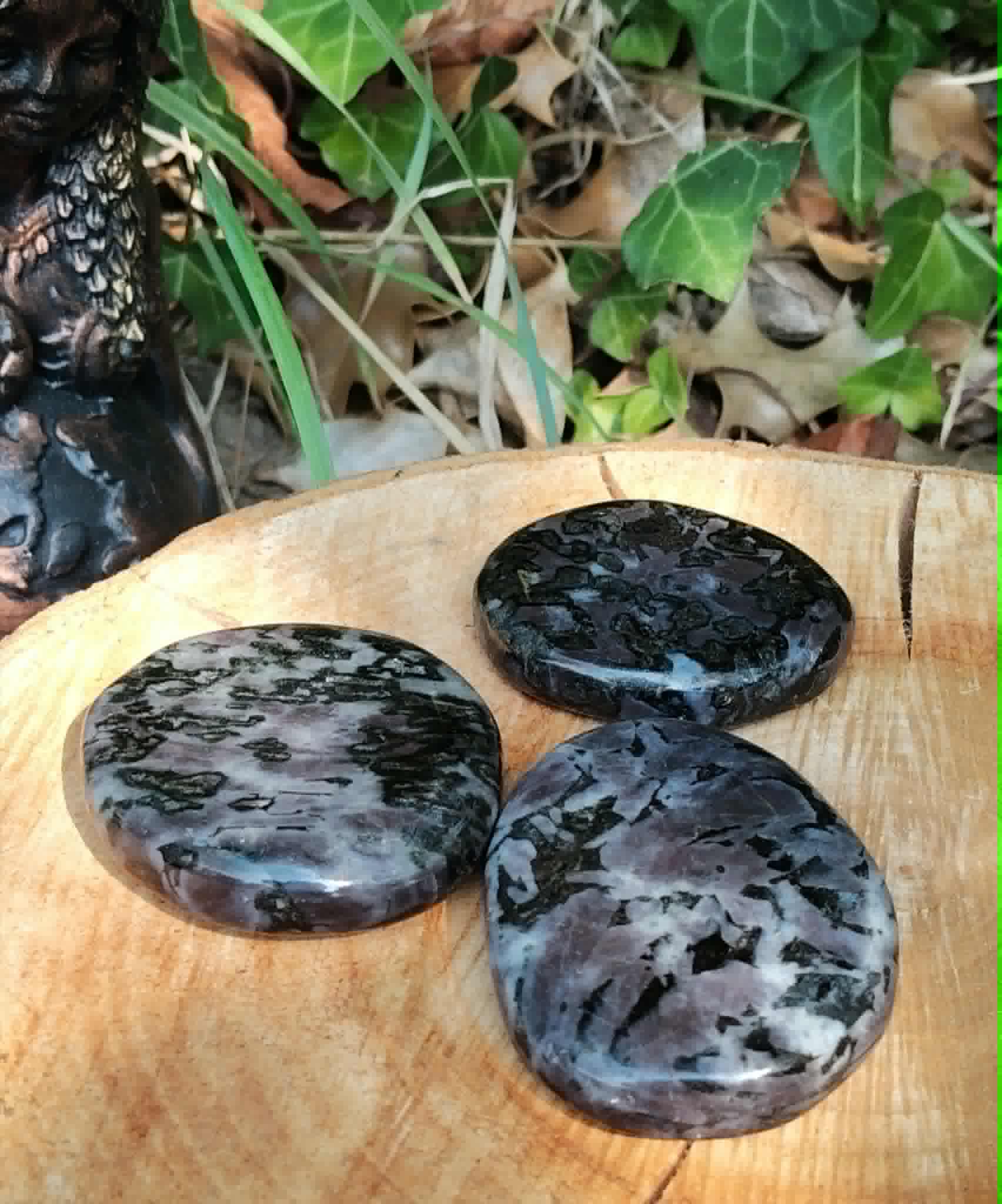 Pierre gabbro merlinite mystique polie avec reflets gris noir et rose pâle, galet naturel associé à l’ancrage profond.