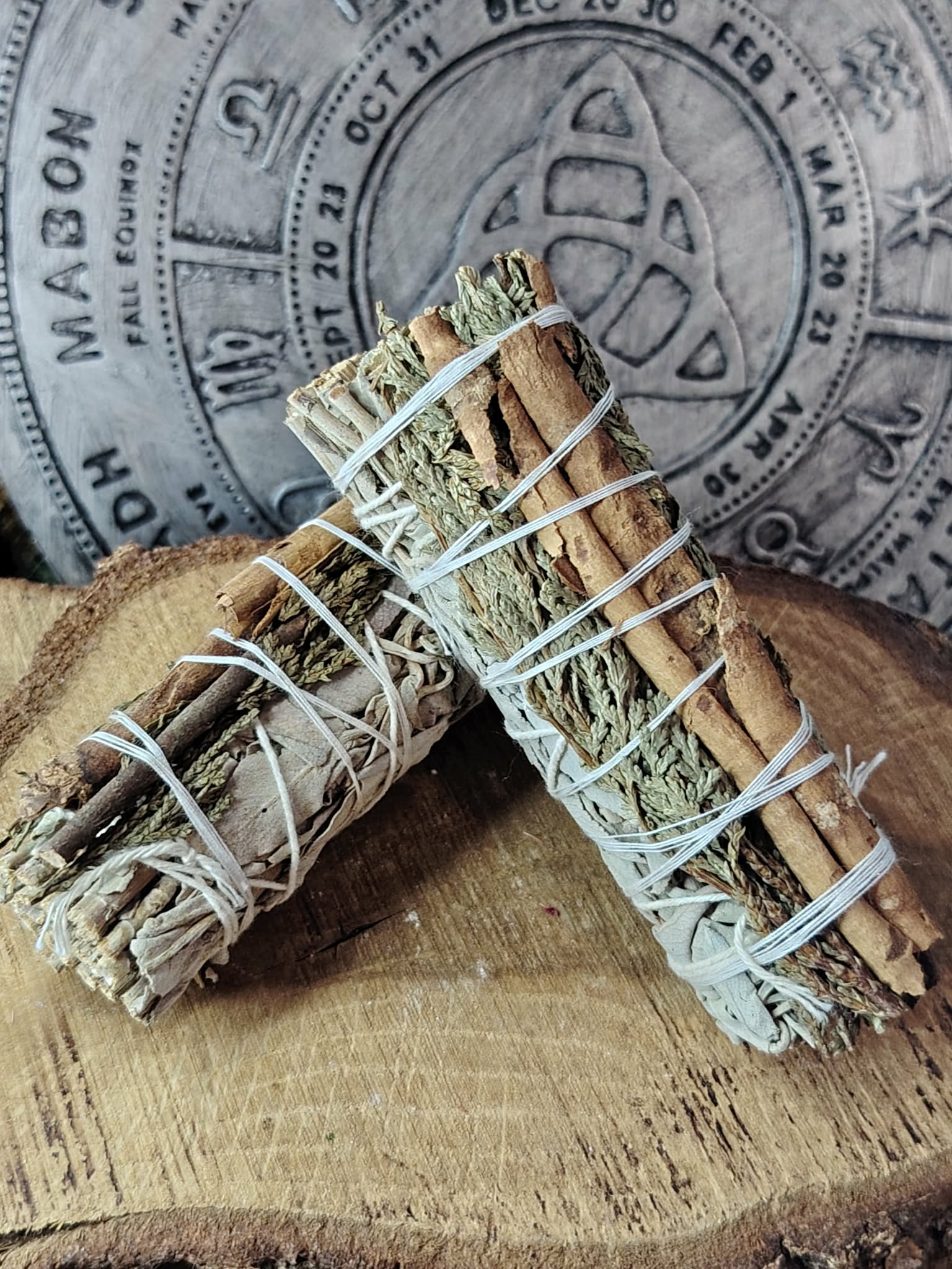 Bâton de purification sauge blanche, cèdre et cannelle présenté avec feuilles séchées et bâton de cannelle pour rituel végétal.