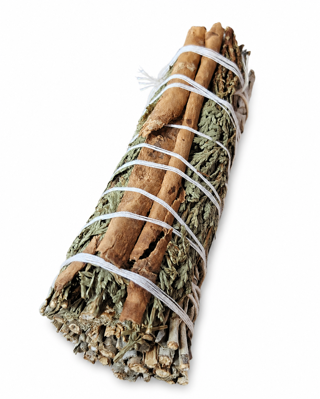 Fagot rituel sauge blanche, cèdre et cannelle sur fond blanc, feuilles argentées et bâton épicé visibles pour purification symbolique.