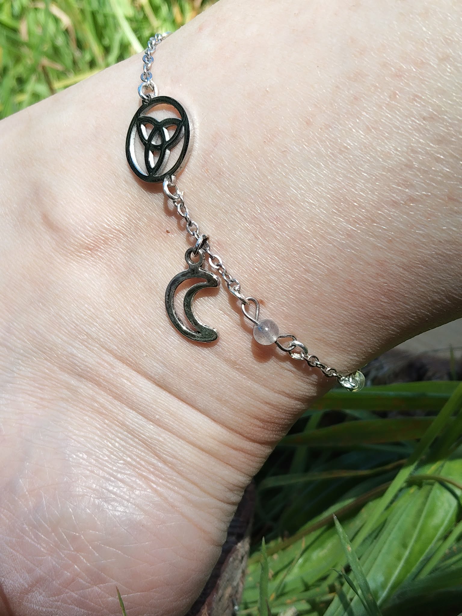 Détail de chaîne de cheville en acier inoxydable, breloque triquetra, lune argentée et petites perles de labradorite aqua aura.