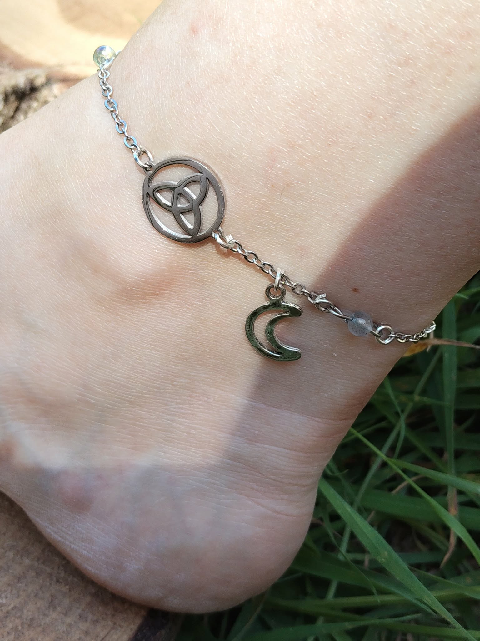 Chaîne de cheville ésotérique argentée avec labradorite, aqua aura, lune et triquetra, style céleste délicat à porter l’été.