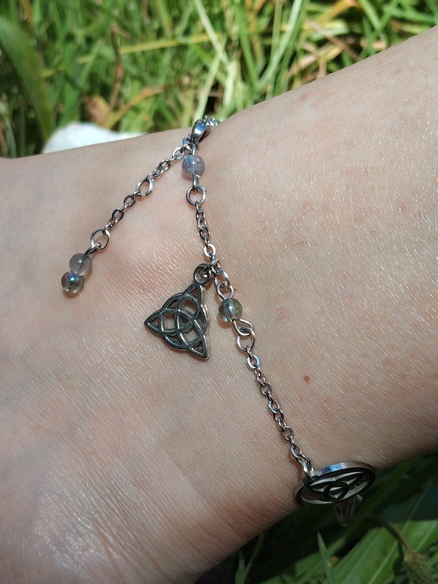 Création Magic Gaïa pour cheville, bijou fin en acier inoxydable avec symboles lunaires, triquetra et pierres aux reflets irisés.