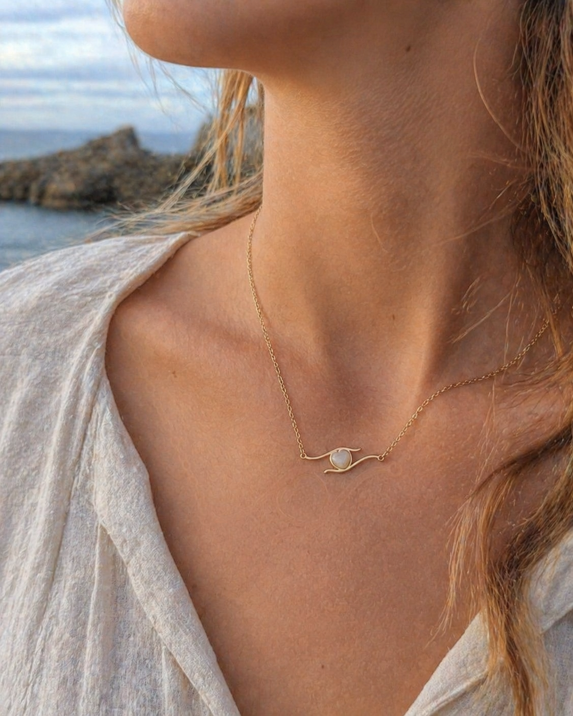 Collier cœur porté au cou en bord de mer, acier inoxydable doré rose pour douceur, amour de soi et élégance discrète.