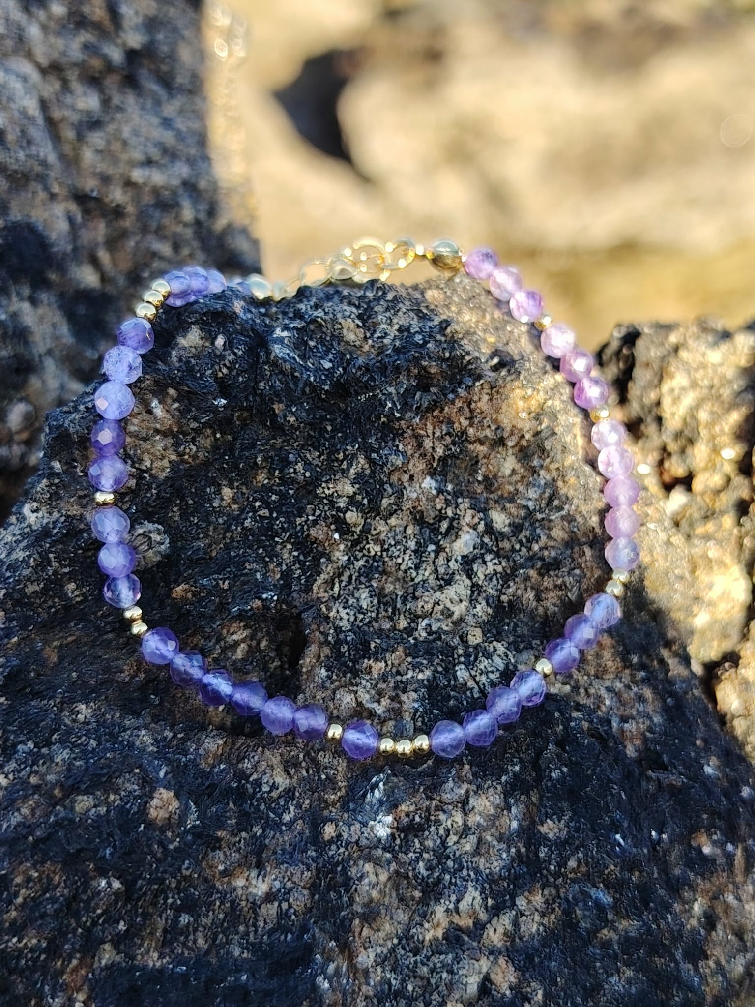 Sélection Magic Gaïa en améthyste facettée sur roche sombre, bracelet lumineux pour recentrage et douceur protectrice.