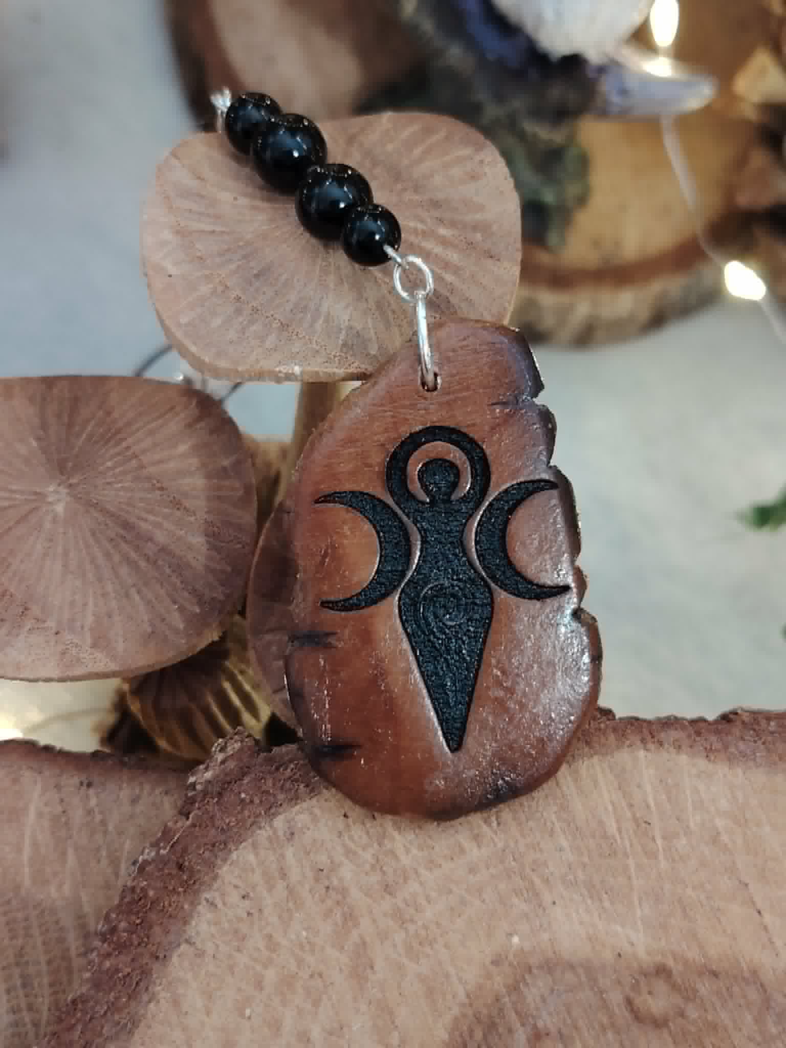 Pendentif bois Gaïa avec perles de tourmaline noire près de champignons décoratifs, bijou de rétroviseur aux accents naturels.