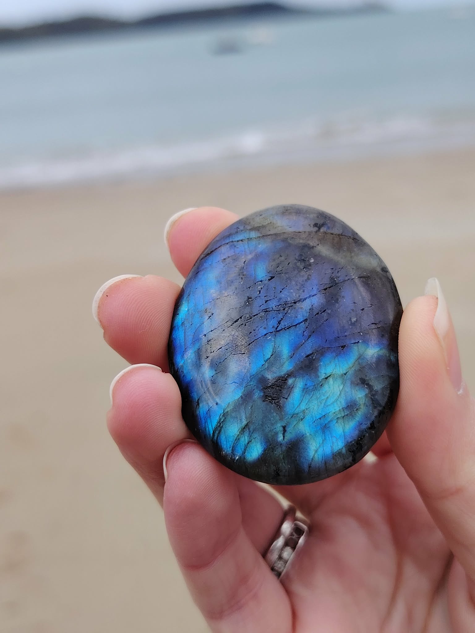 Galet de labradorite dans la main, pierre polie aux éclats bleutés pour apaisement et équilibre énergétique.
