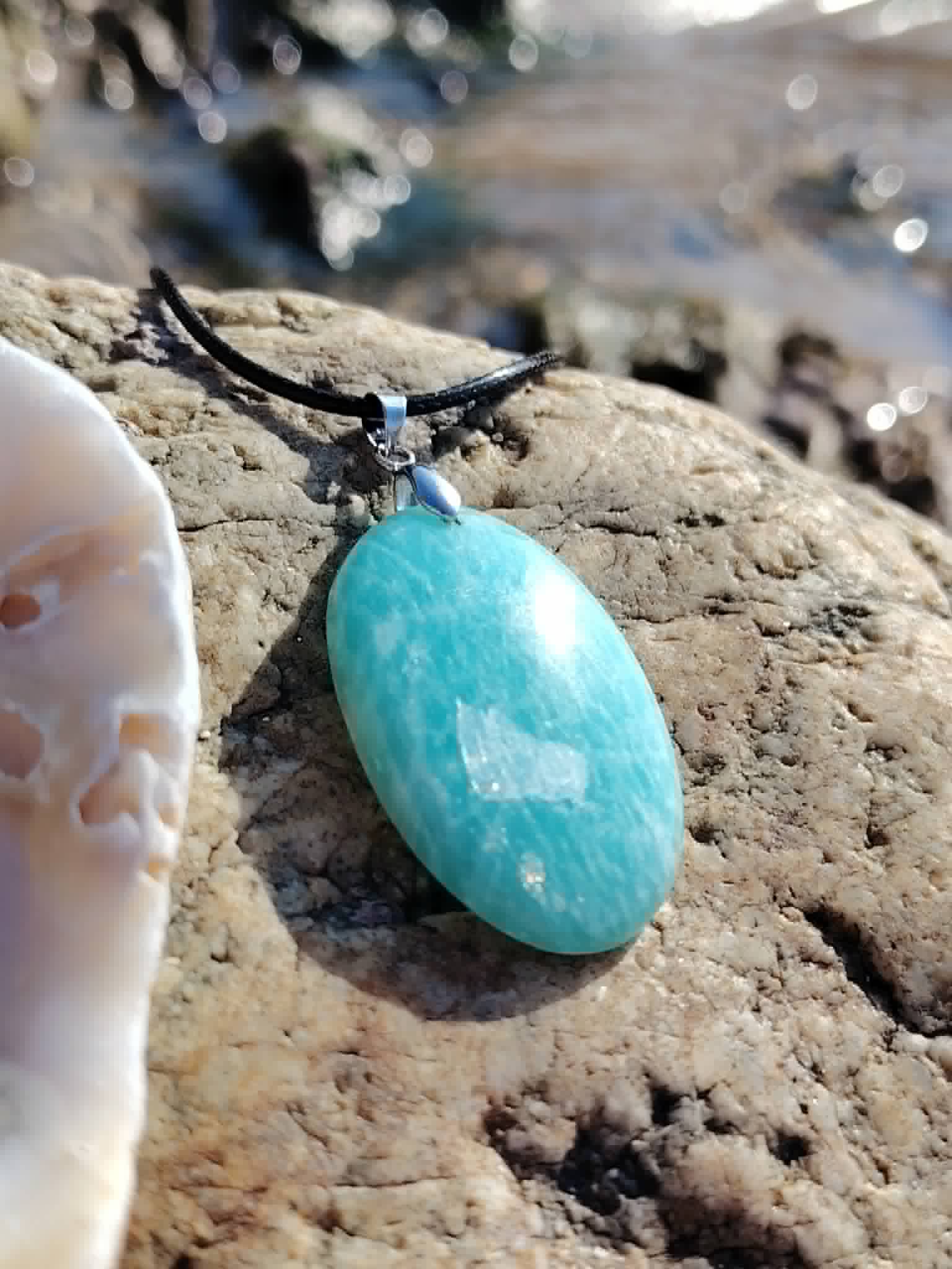 Pendentif Amazonite porté au cou, bijou bleu-vert sur tenue blanche pour communication sincère et clarté intérieure.