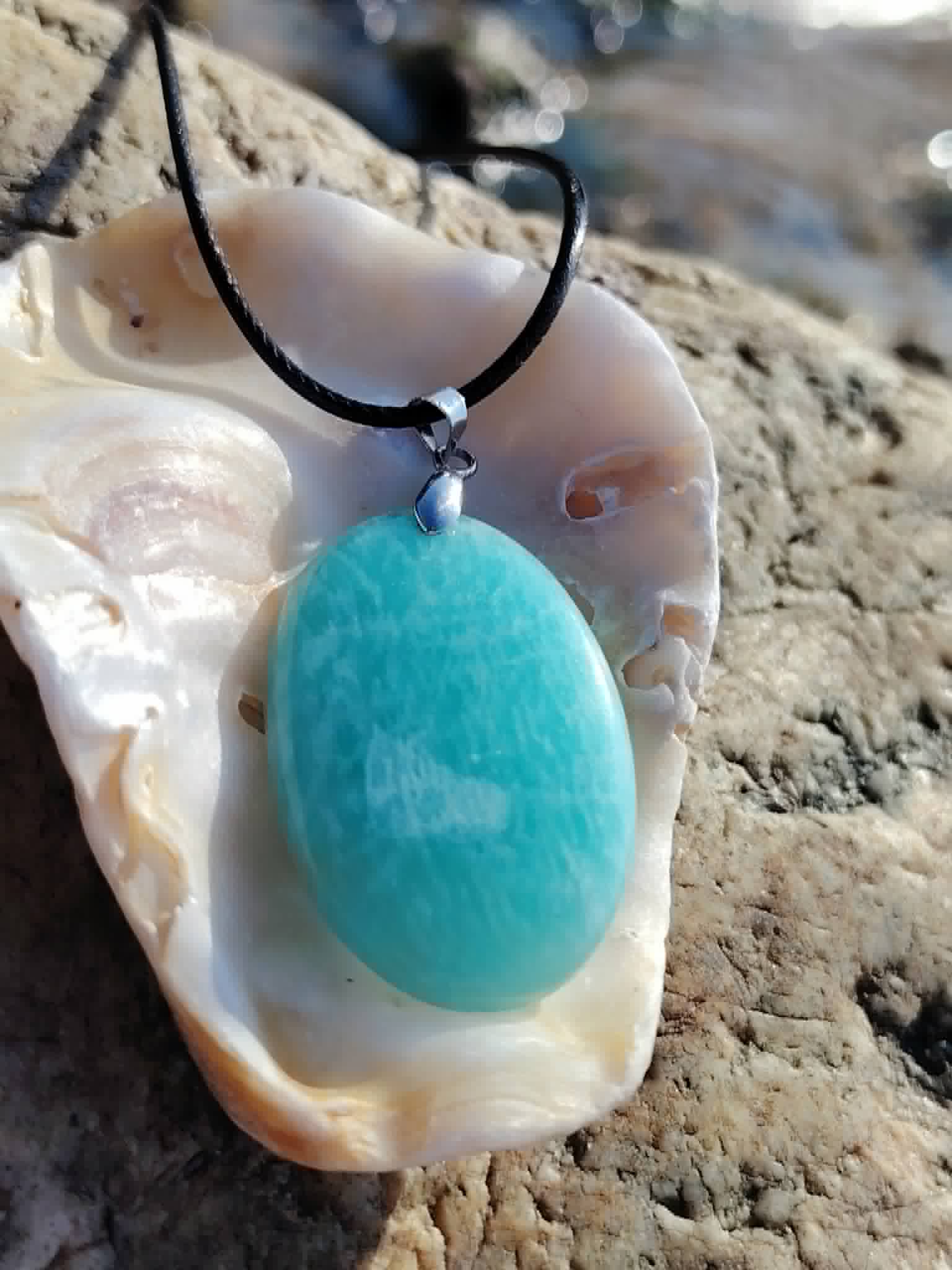 Bijou Amazonite présenté dans un coquillage naturel, pendentif bleu-vert pour harmonie du cœur et parole apaisée.