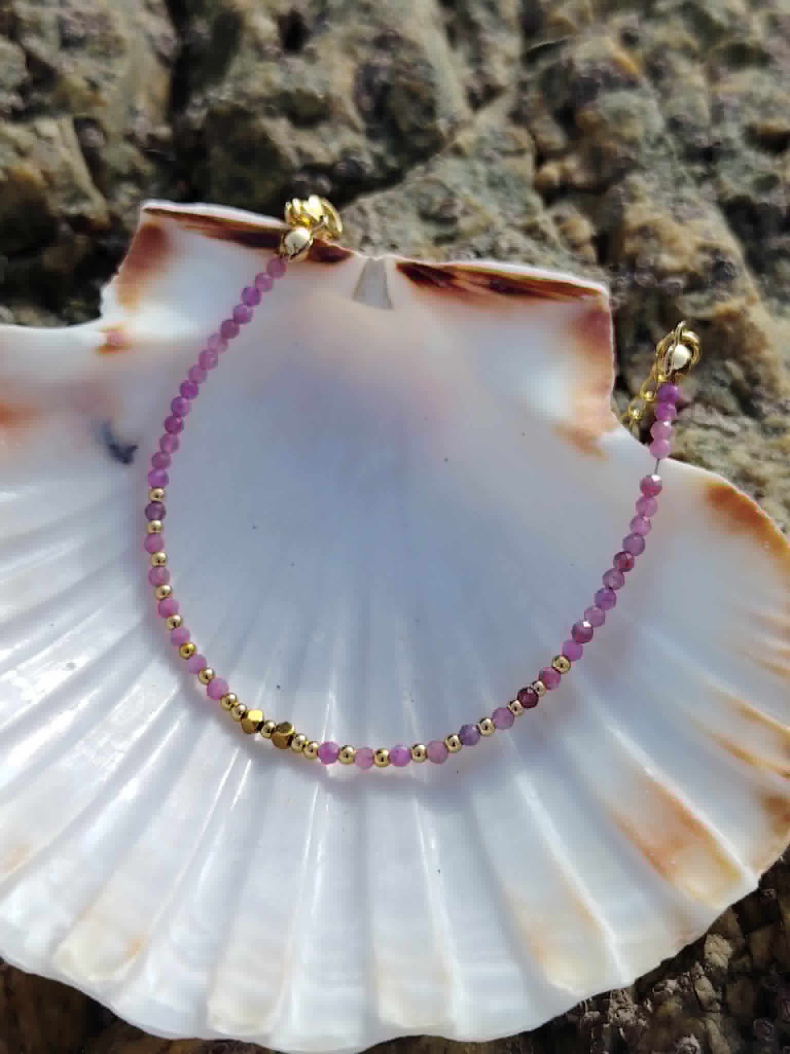 Bracelet Tourmaline rose facettée 2 mm posé sur coquillage blanc en bord de mer en Bretagne, cuivre plaqué or et douceur du cœur.