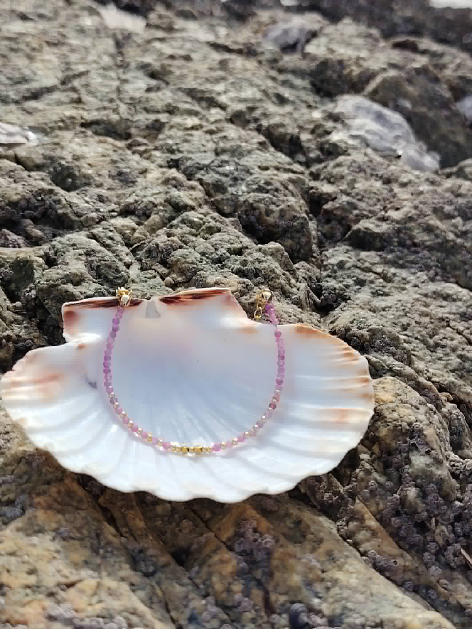 Bracelet rose et doré dans un coquillage sur rochers bretons, perles facettées 2 mm pour apaisement du cœur.