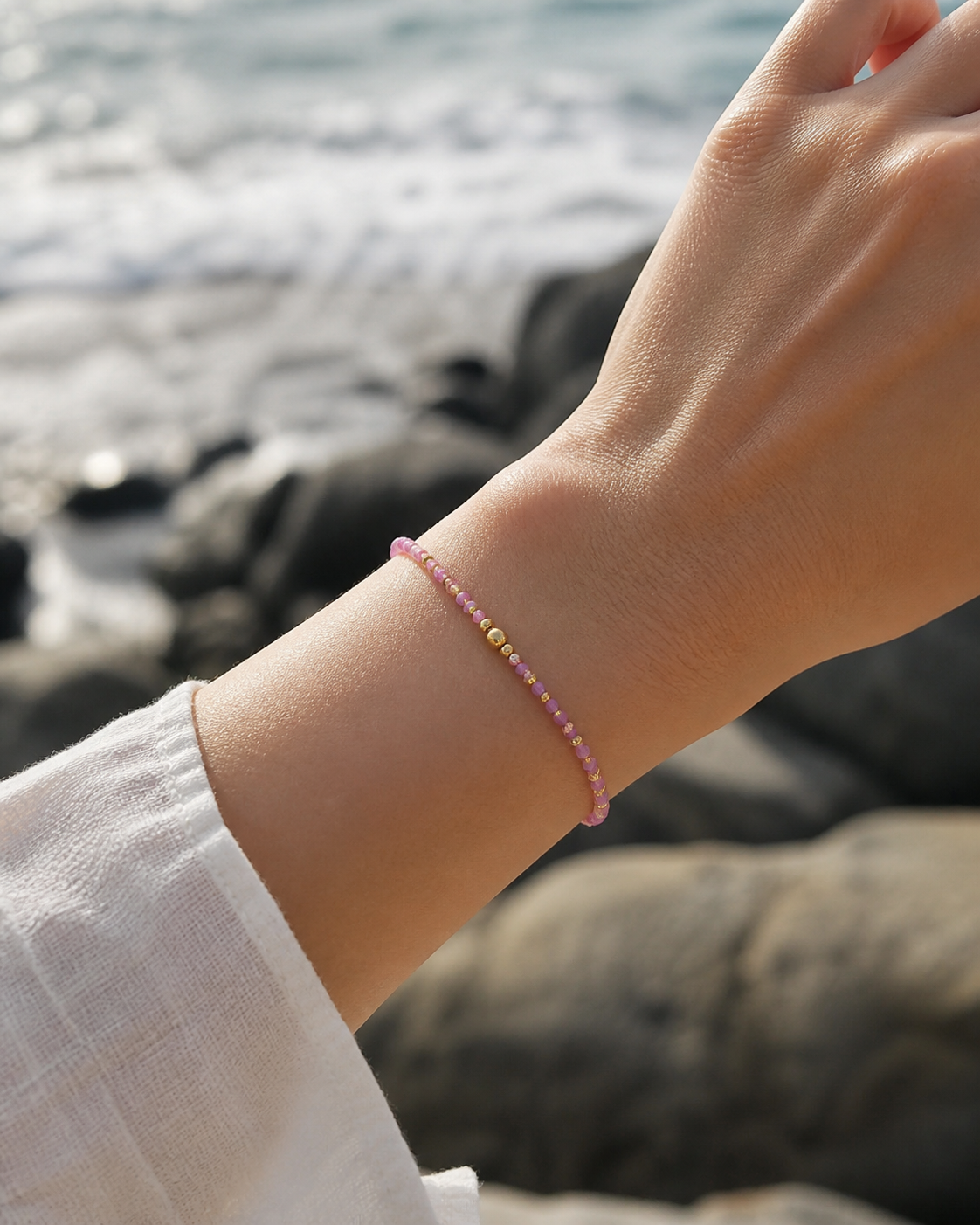 Bracelet Tourmaline rose porté au poignet face à la mer, bijou fin en cuivre plaqué or pour tendresse intérieure.