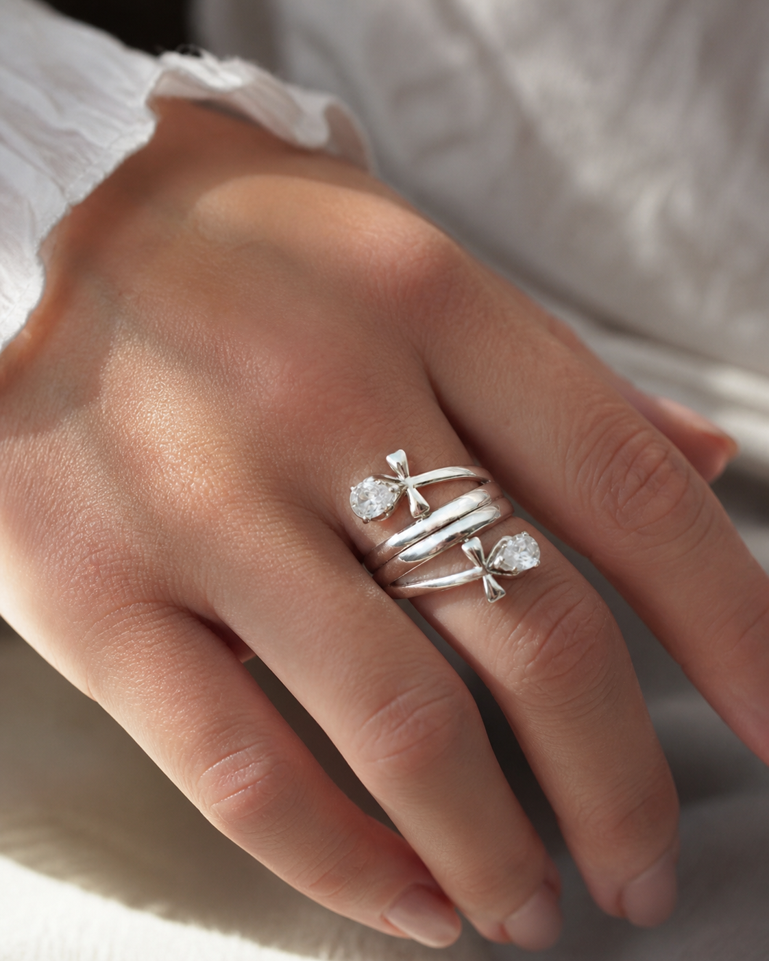 Bague argentée motif Ankh stylisé portée à la main, acier inoxydable lumineux et strass goutte pour force de vie.