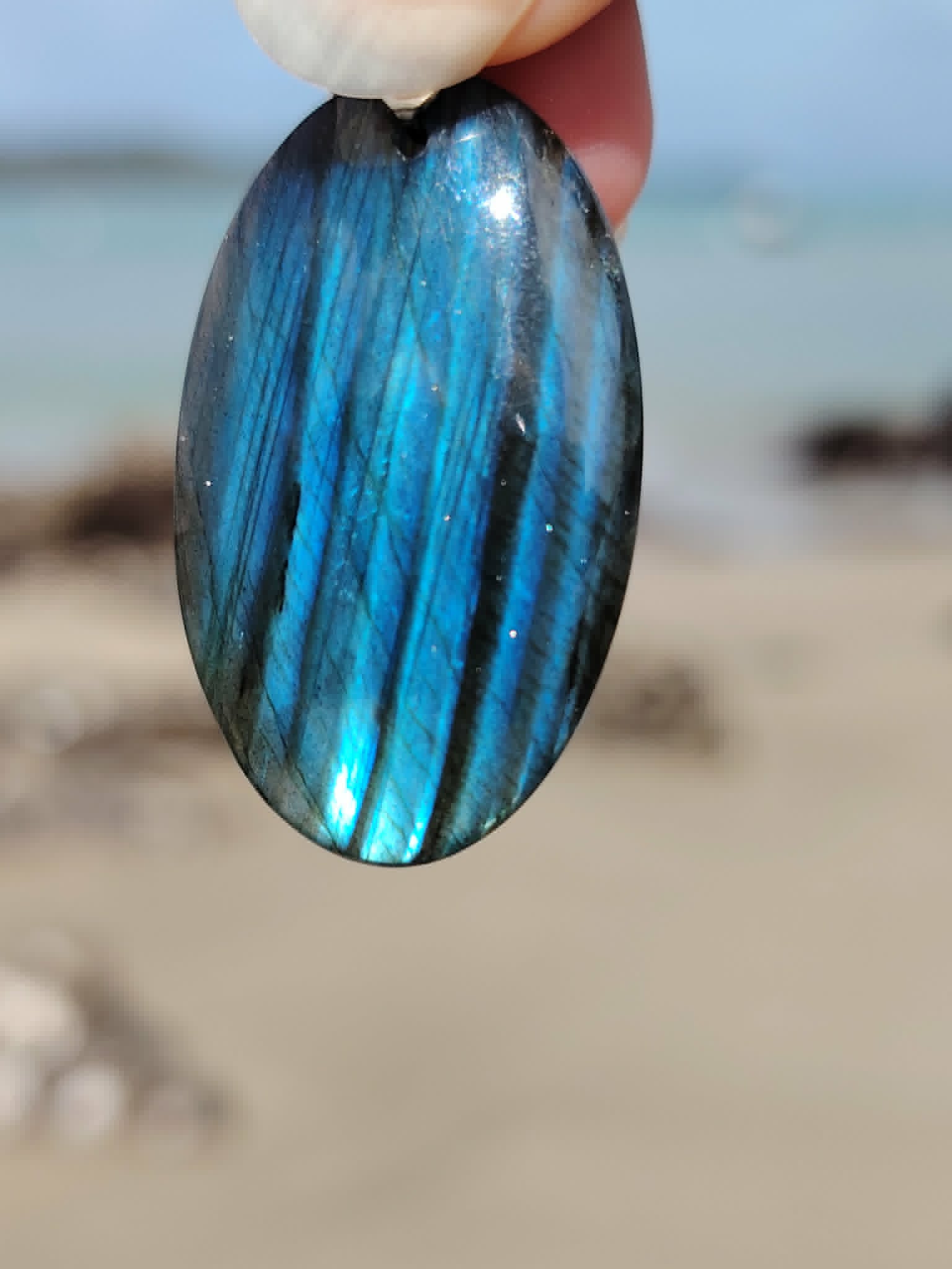 Pendentif Labradorite bleue sur décor minéral en Bretagne, flash naturel changeant pour recentrage et énergie douce.