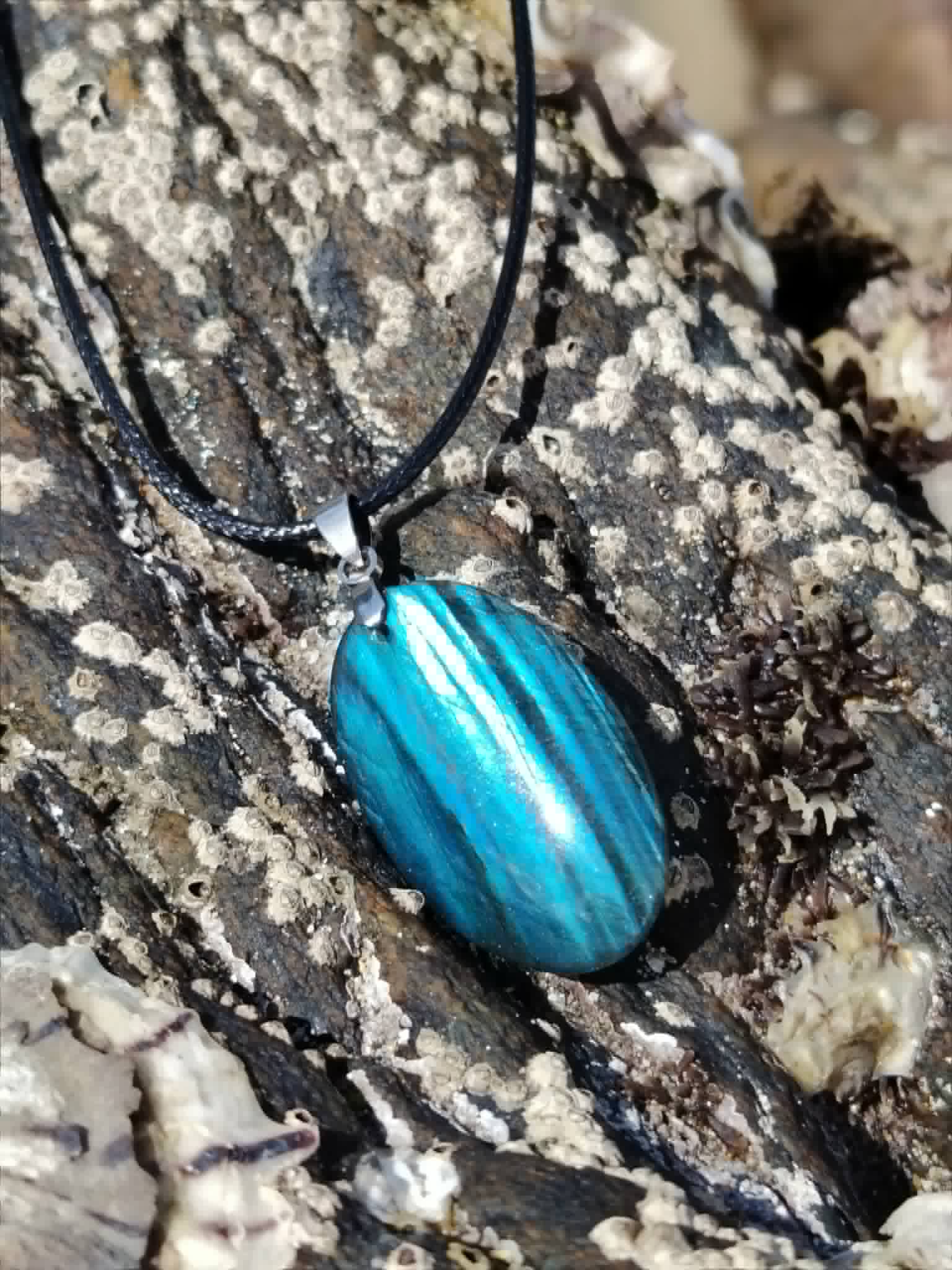 Pendentif Labradorite bleue posé sur rocher marin en Bretagne, reflets turquoise pour calme intérieur et intuition.