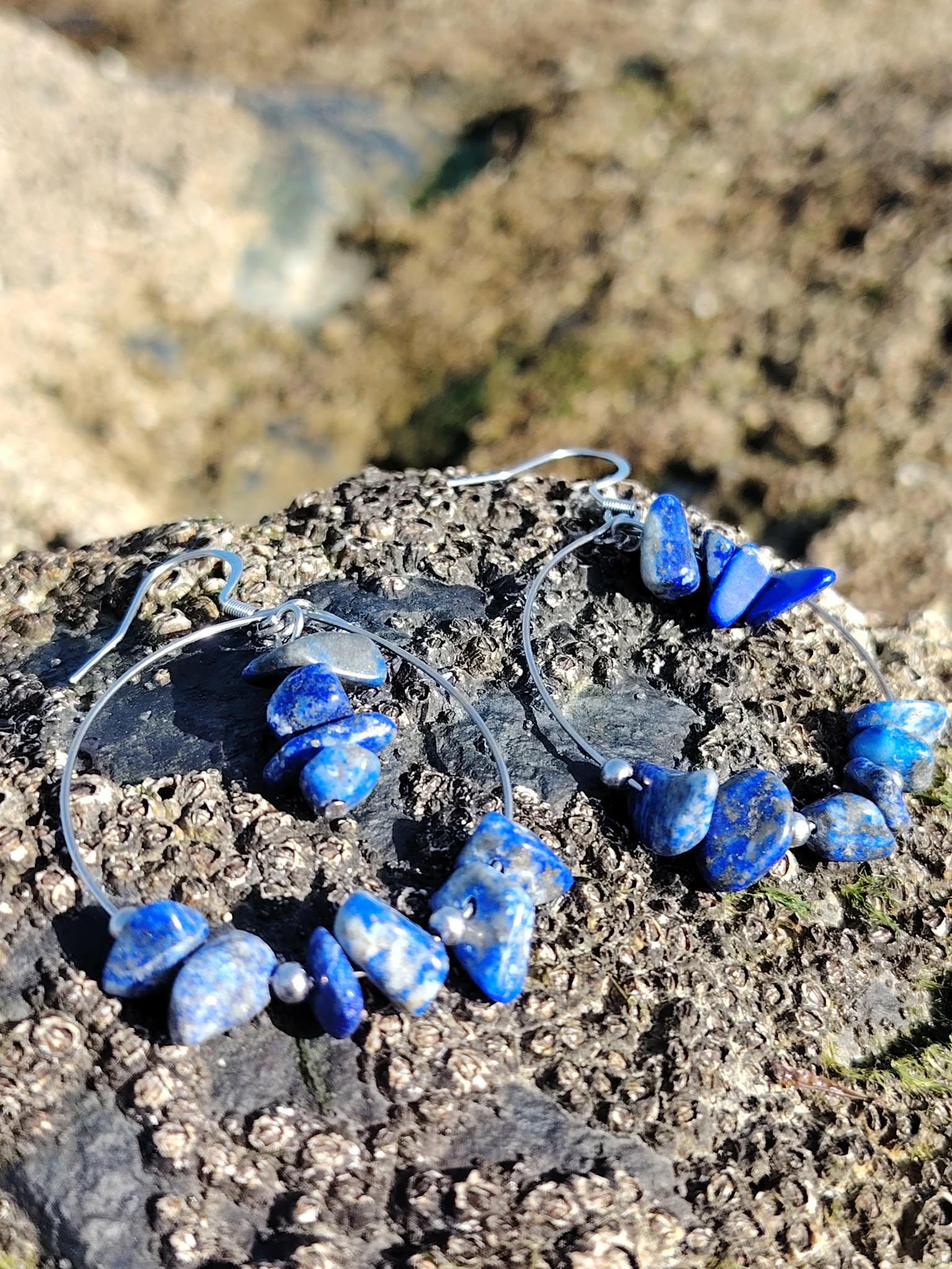 Bijou d’oreilles Lapis-Lazuli création Magic Gaïa photographié sur roche de bord de mer, bleu intense et esprit bohème naturel.