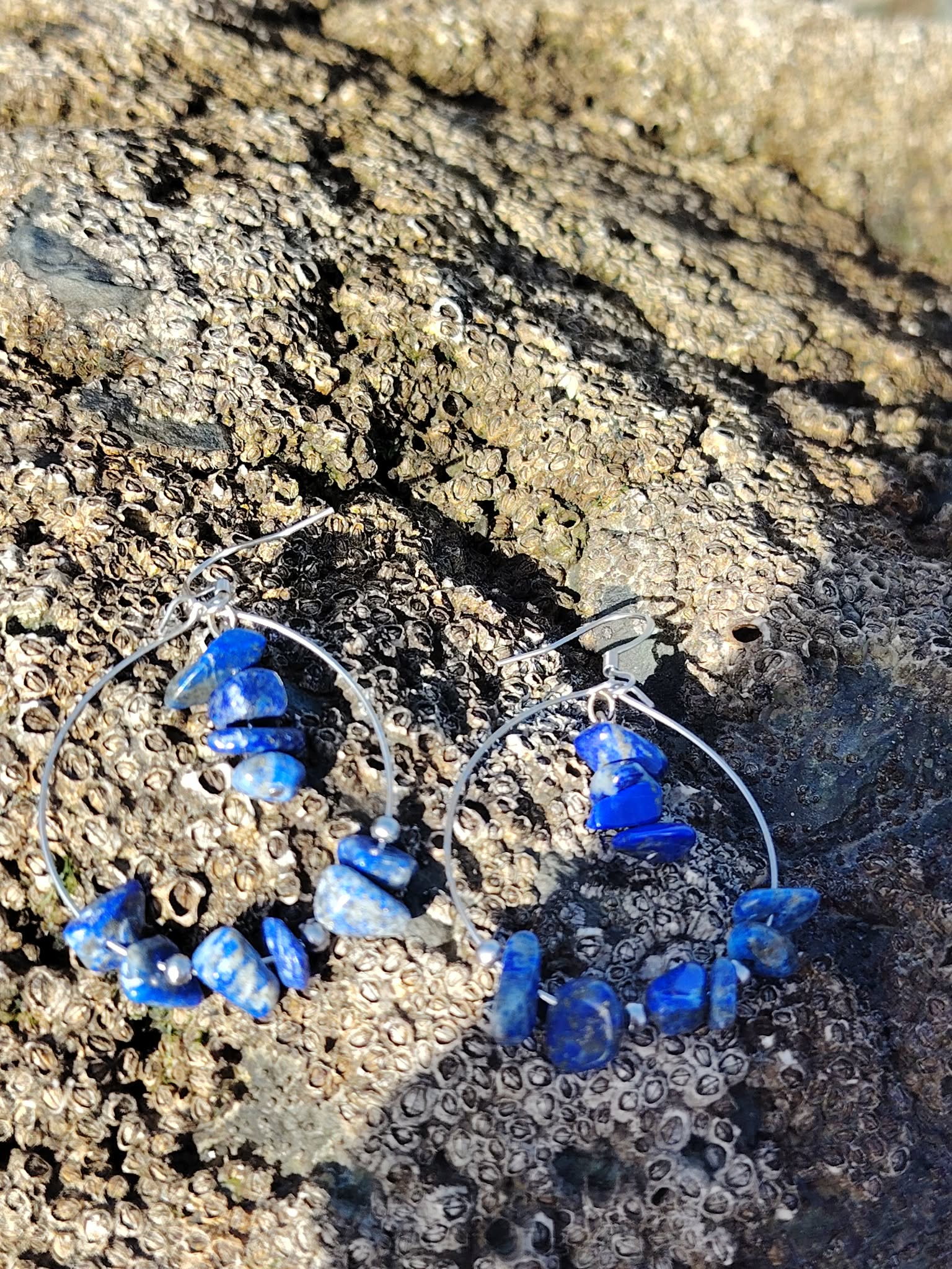 Détail des boucles Lapis-Lazuli Magic Gaïa sur rocher du littoral breton, perles chips naturelles aux reflets bleu profond.
