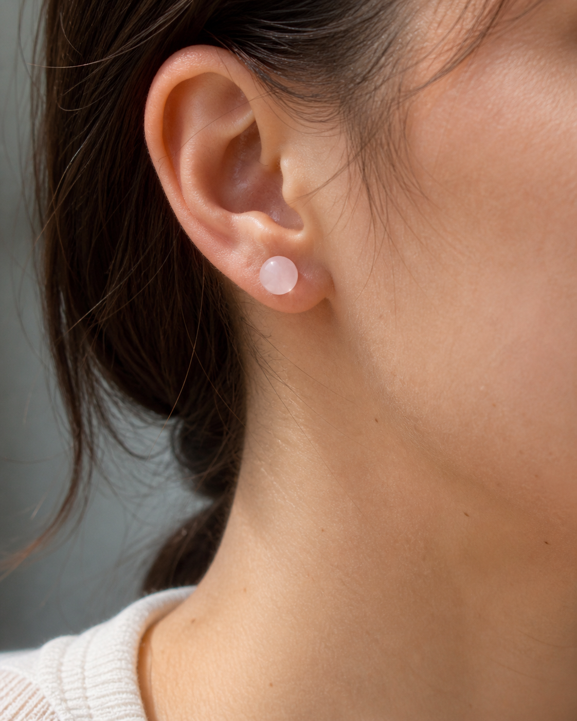 Puces Quartz Rose portées à l’oreille, bijou discret en acier inoxydable pour apaisement émotionnel et tendresse.