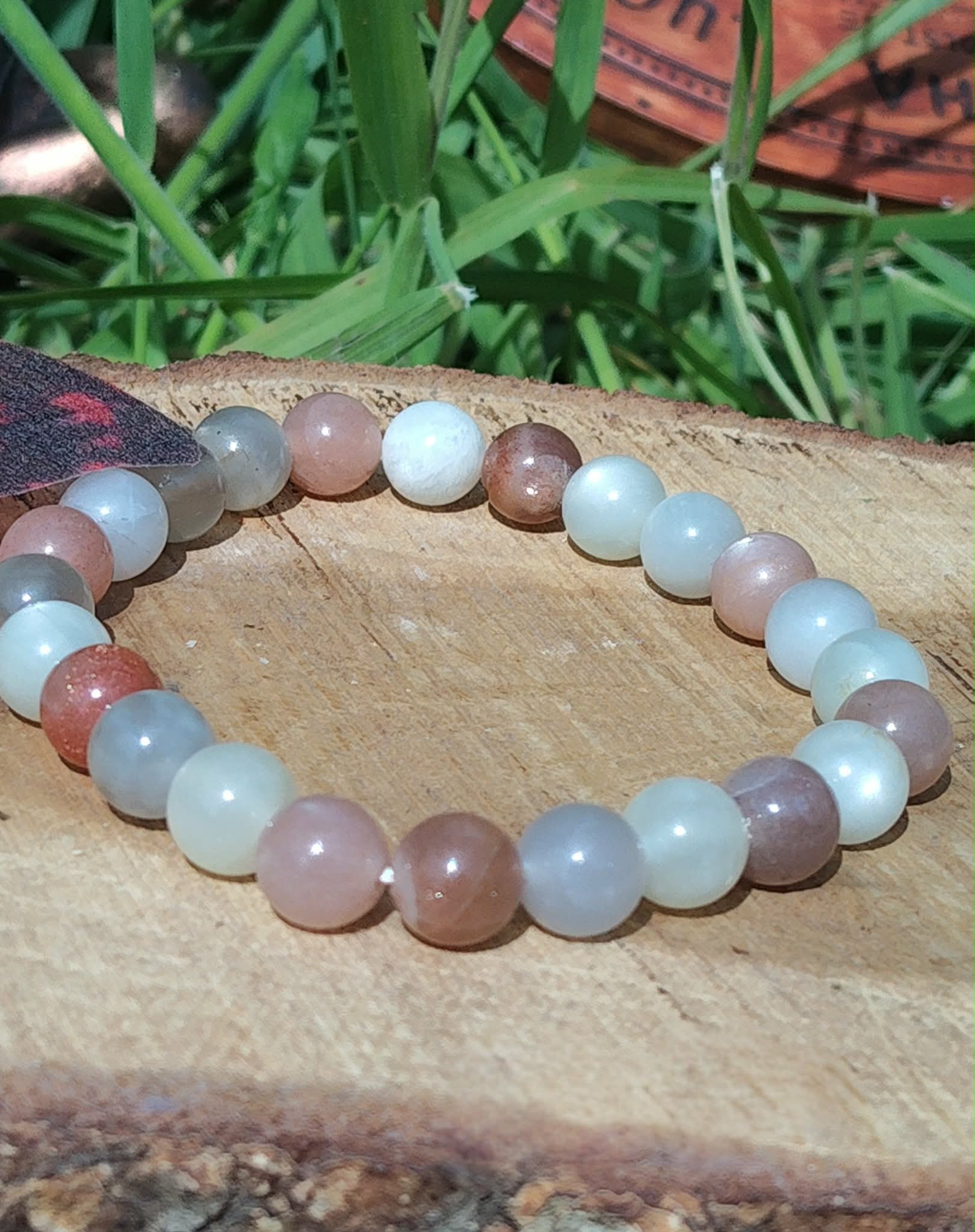 Bracelet Pierre de Lune beige multicolore sur rondin de bois, perles crème, pêche, gris doux et blanc laiteux pour intuition et équilibre émotionnel.