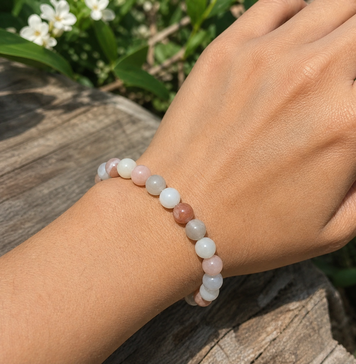 Bracelet Pierre de Lune beige multicolore porté au poignet en extérieur, bijou pastel pour douceur, féminité symbolique et nouveaux départs.
