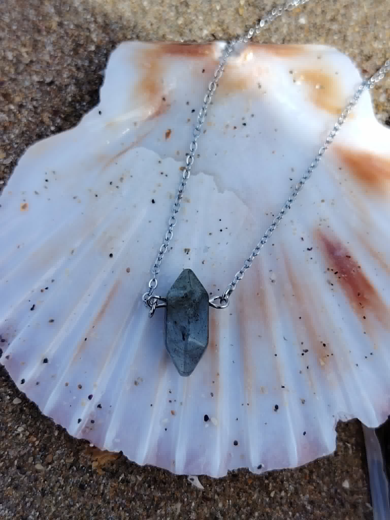 Pendentif Labradorite gris bleuté sur coquillage blanc, forme pointe et chaîne argentée pour un style minéral doux et protecteur.
