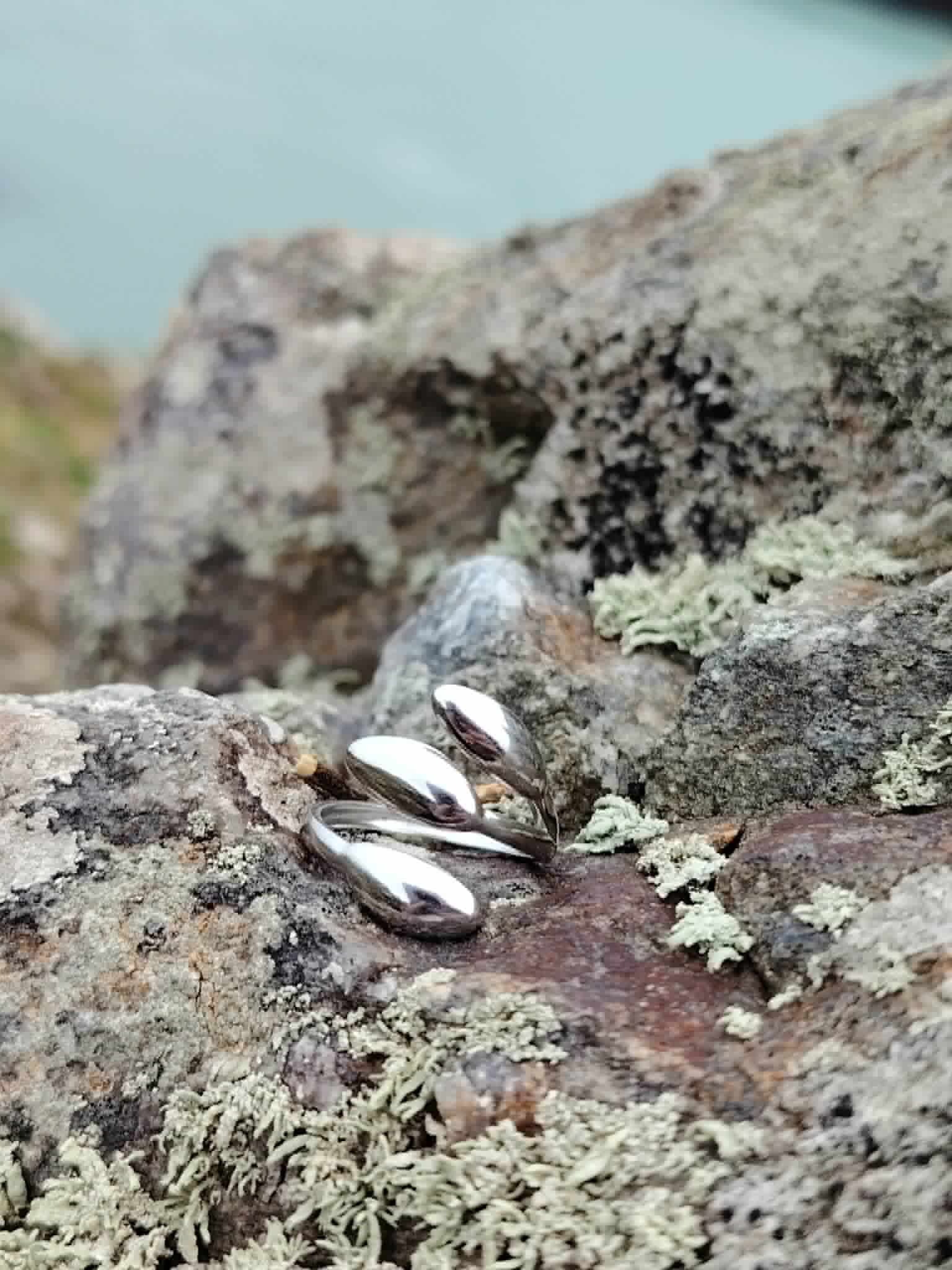 Bague acier inoxydable argenté posée en décor naturel, forme triple goutte brillante pour une main élégante.