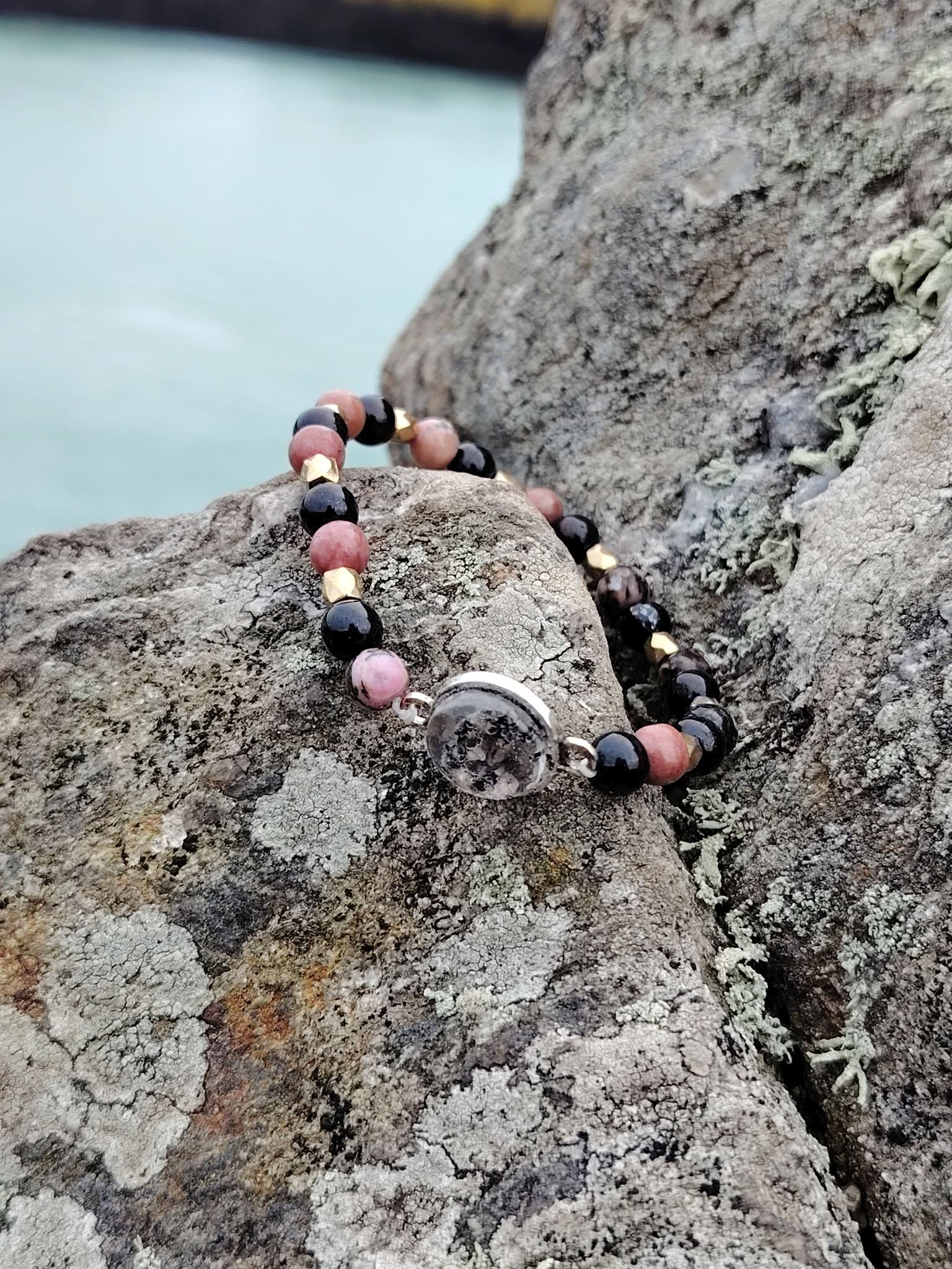 Bracelet en Rhodonite et Tourmaline Noire présenté en lumière naturelle, perles contrastées rose et noir avec cabochon central.