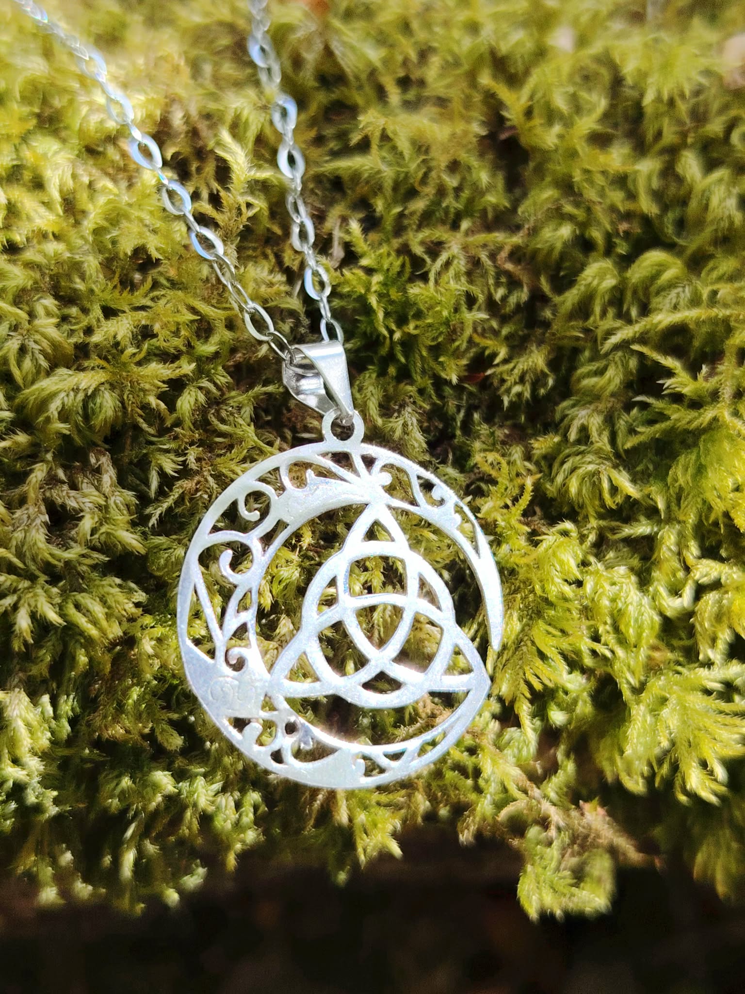 Pendentif Triquetra Lune sur mousse verte, argent 925 lumineux avec croissant lunaire et entrelacs celtiques.