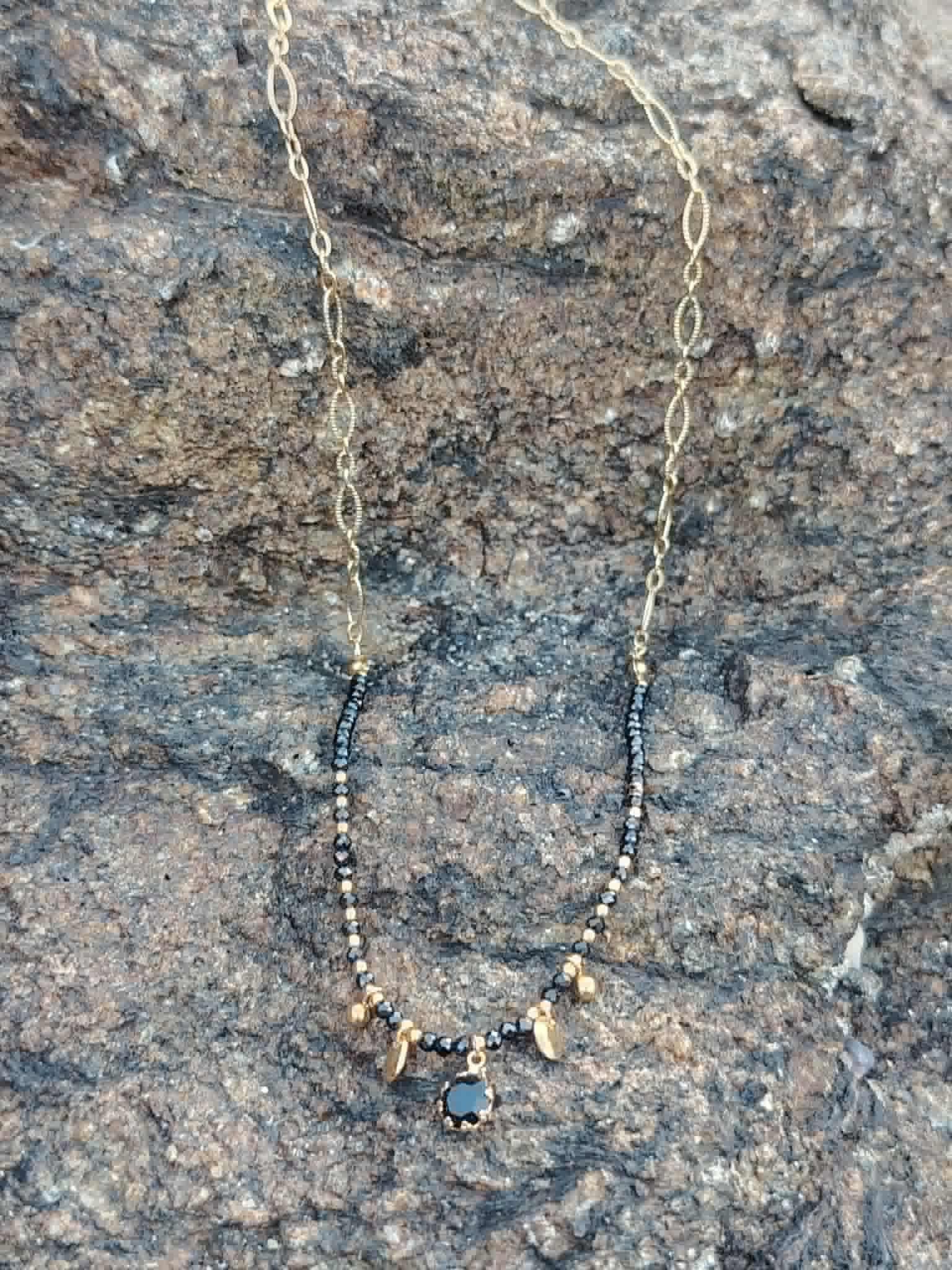 Collier doré en acier inoxydable avec Onyx naturel, strass noir central et petites pierres noires au style chic et mystique.