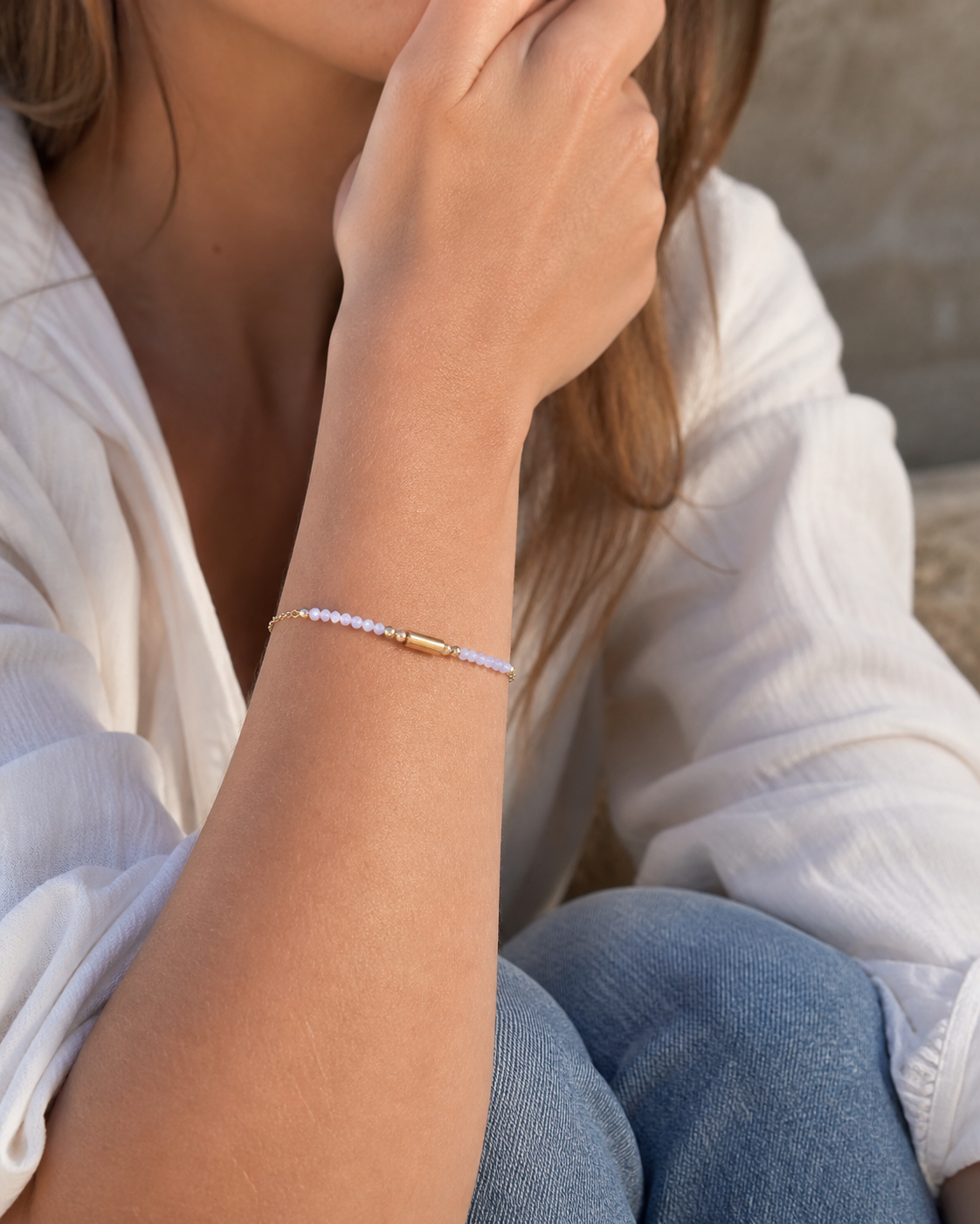 Bracelet Améthyste porté au poignet, perles lilas facettées, chaîne dorée et breloque centrale pour calme intérieur.