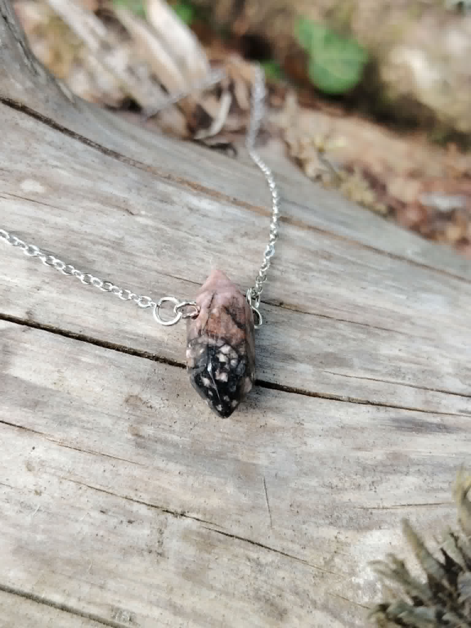 Gros plan sur pendentif pointe Rhodonite avec chaîne acier inoxydable, pierre polie rose et noire pour tendresse et recentrage.