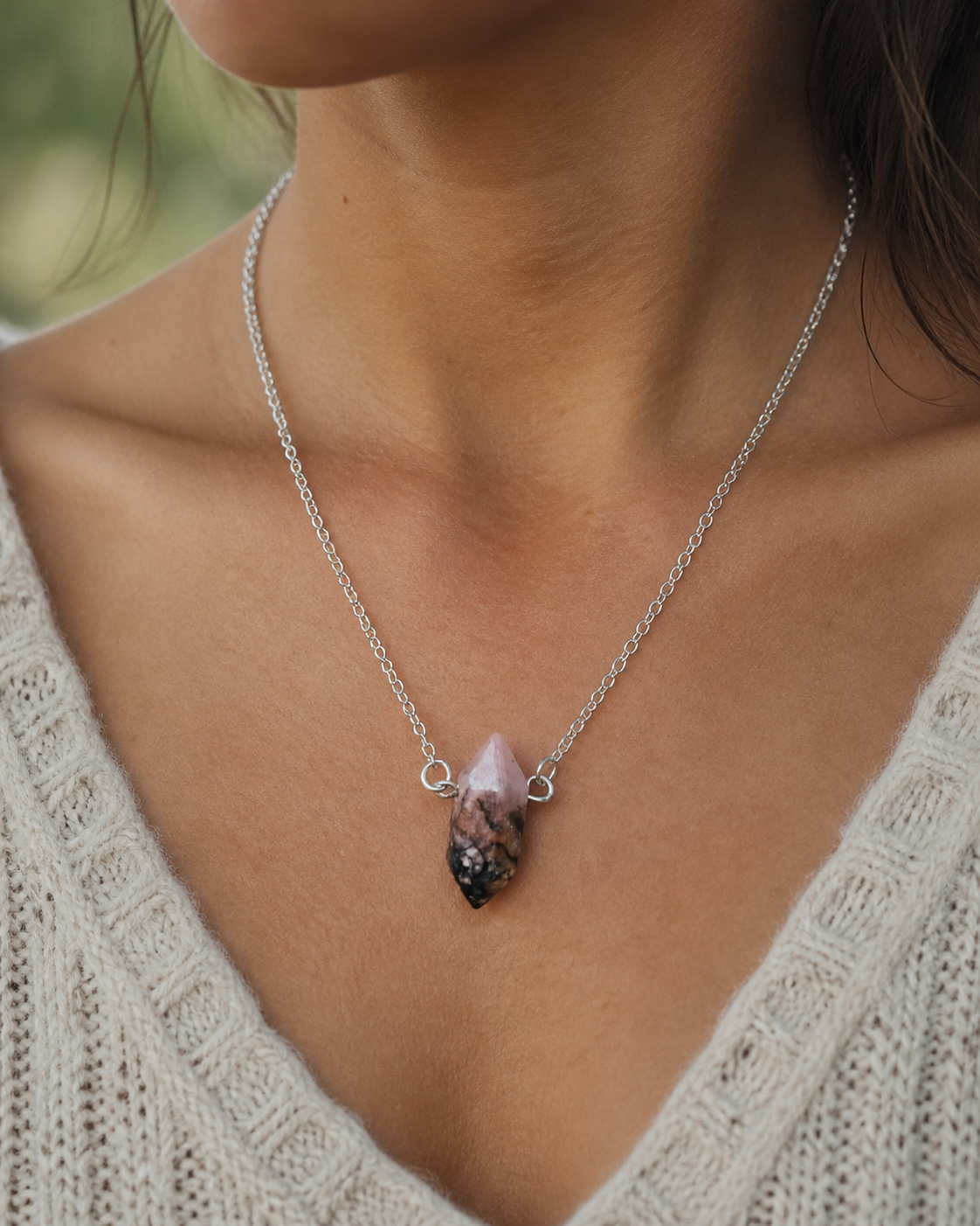 Pendentif pointe Rhodonite porté au cou, chaîne argentée et pierre rose veinée pour apaisement émotionnel et amour de soi.