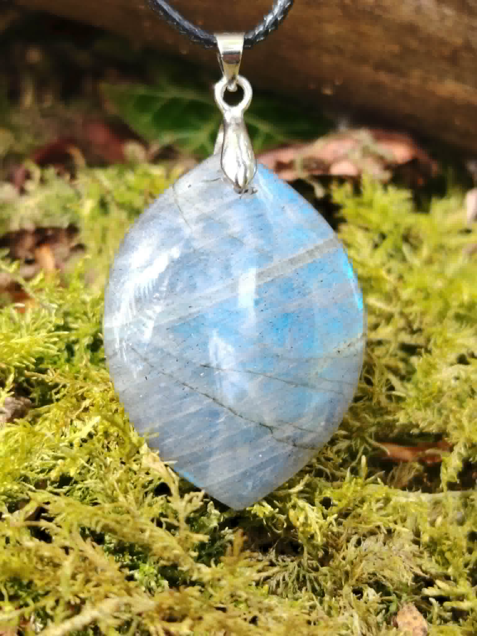 Pendentif labradorite marquise suspendu devant la mousse, éclats bleu clair et présence apaisante en décor breton.